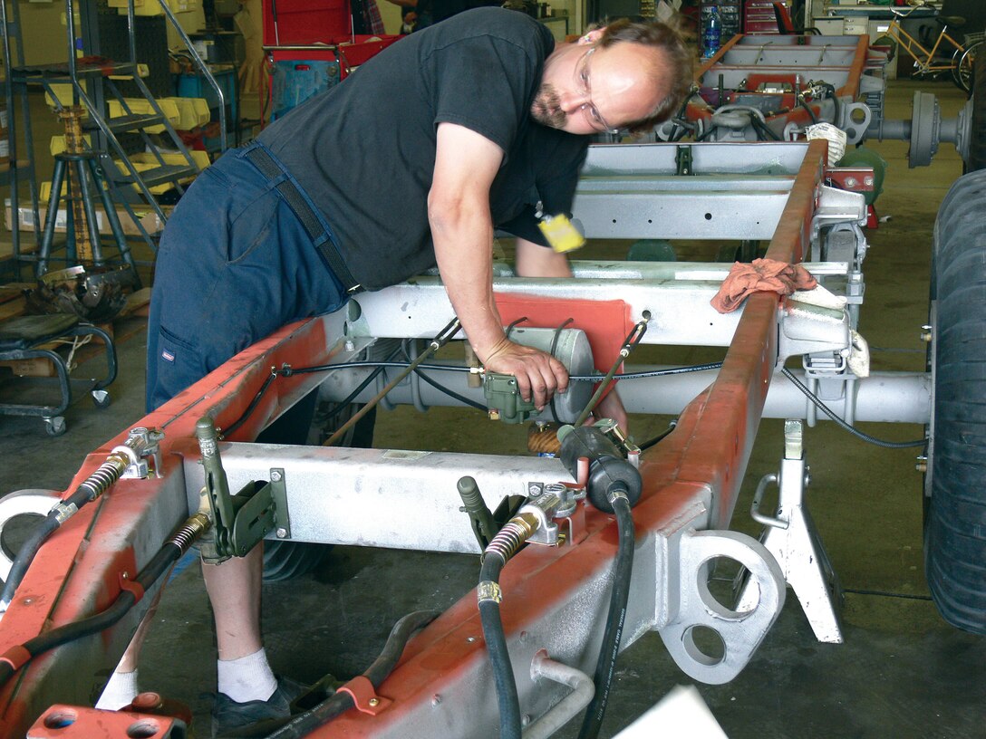 Richard Shabel, a heavy mobile equipment mechanic at Maintenance Center Barstow aboard Marine Corps Logistics Base Barstow, adjusts the air tank on the M-105 trailer that controls the breakaway braking system. The system locks up the brakes if the trailer ever becomes detached from the vehicle towing it.