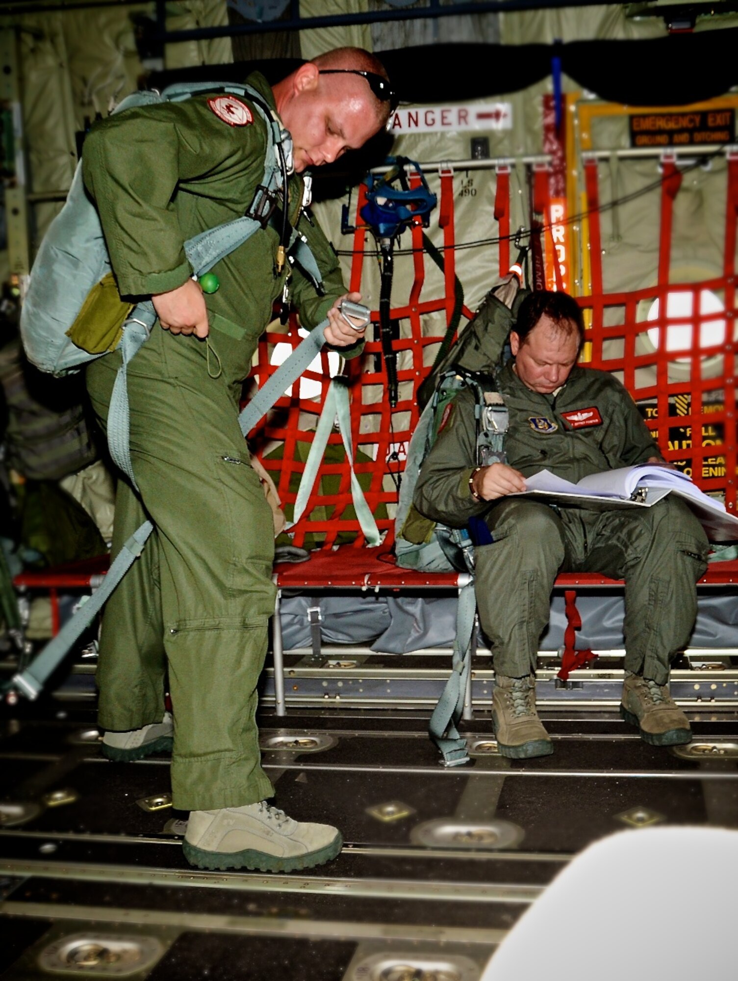 Staff Sgt. Chris Caso adjusts his gear while Staff Sgt. Jeff Fountain reads up on procedures before the training mission. They are loadmasters with the 815th AS.   (U.S. Air Force photo by Tech. Sgt. Tanya King)
