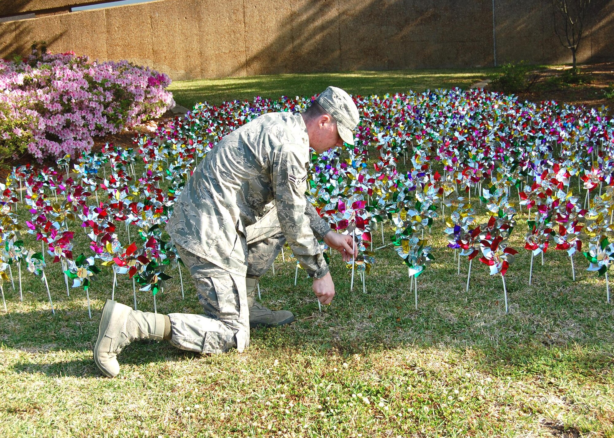 Airman 1st Class Philip Mazzie, 81st Medical Operations Squadron mental health flight family advocacy program staff, places pinwheels in the front of the hospital April 13.  (U.S. Air Force photo by Steve Pivnick)