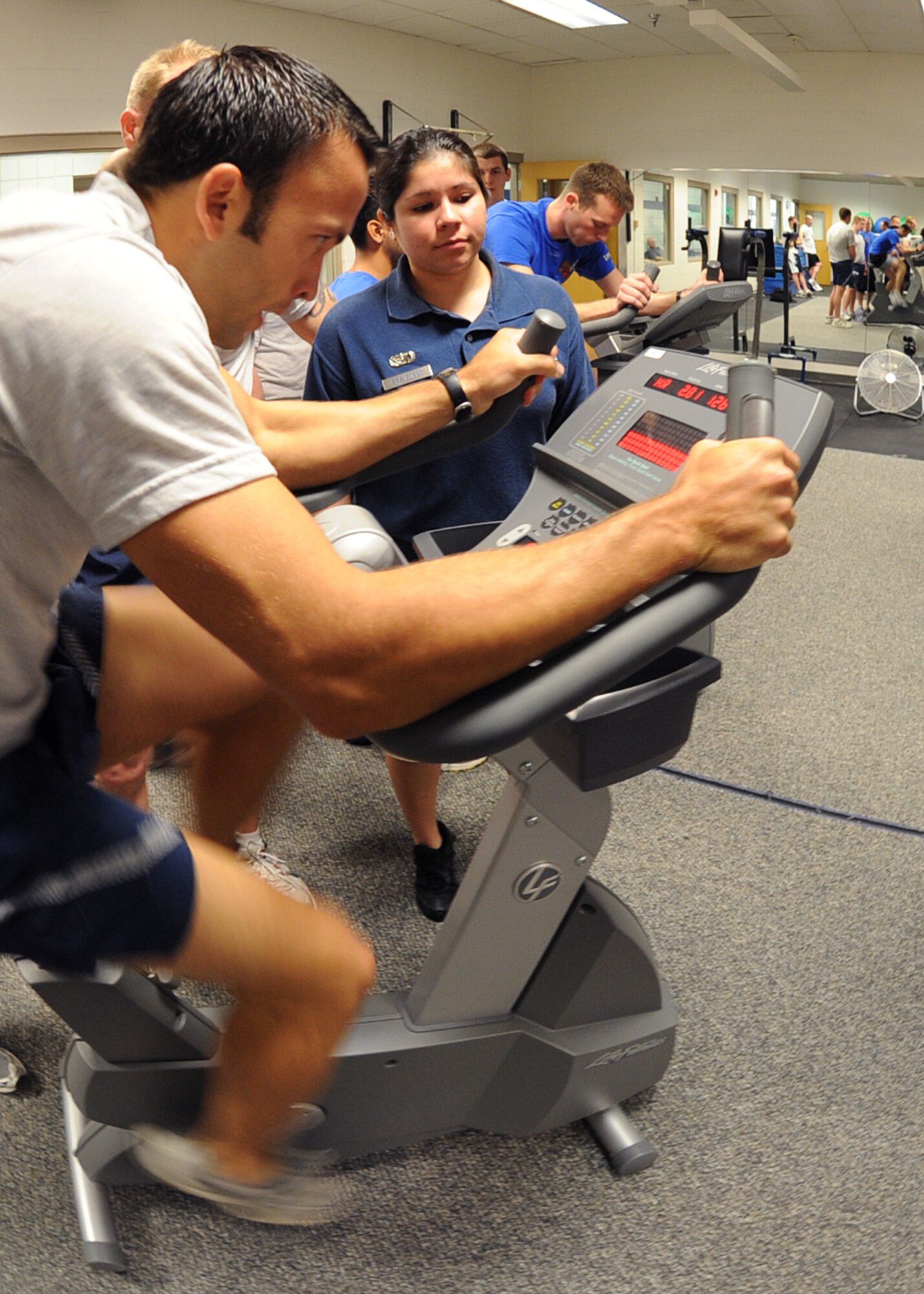 Capt. John Finke, 384th Air Refueling Squadron assistant chief of scheduling, pedals during a three mile bike ride while Senior Airman Elisa Bueno, 22nd Force Support Squadron fitness journeyman, annotates the time April 22, 2010, McConnell Air Force Base, Kan. Team McConnell Airmen participated in an indoor triathlon that included a quarter mile swim, three mile bike run and 1 1/2 run, as part of McConnell’s Warrior Day. The winner for the triathlon was the 22nd Aircraft maintenance Squadron with a total time of 21 minutes and three seconds. (U.S. Air Force photo/Senior Airman Maria Ruiz)