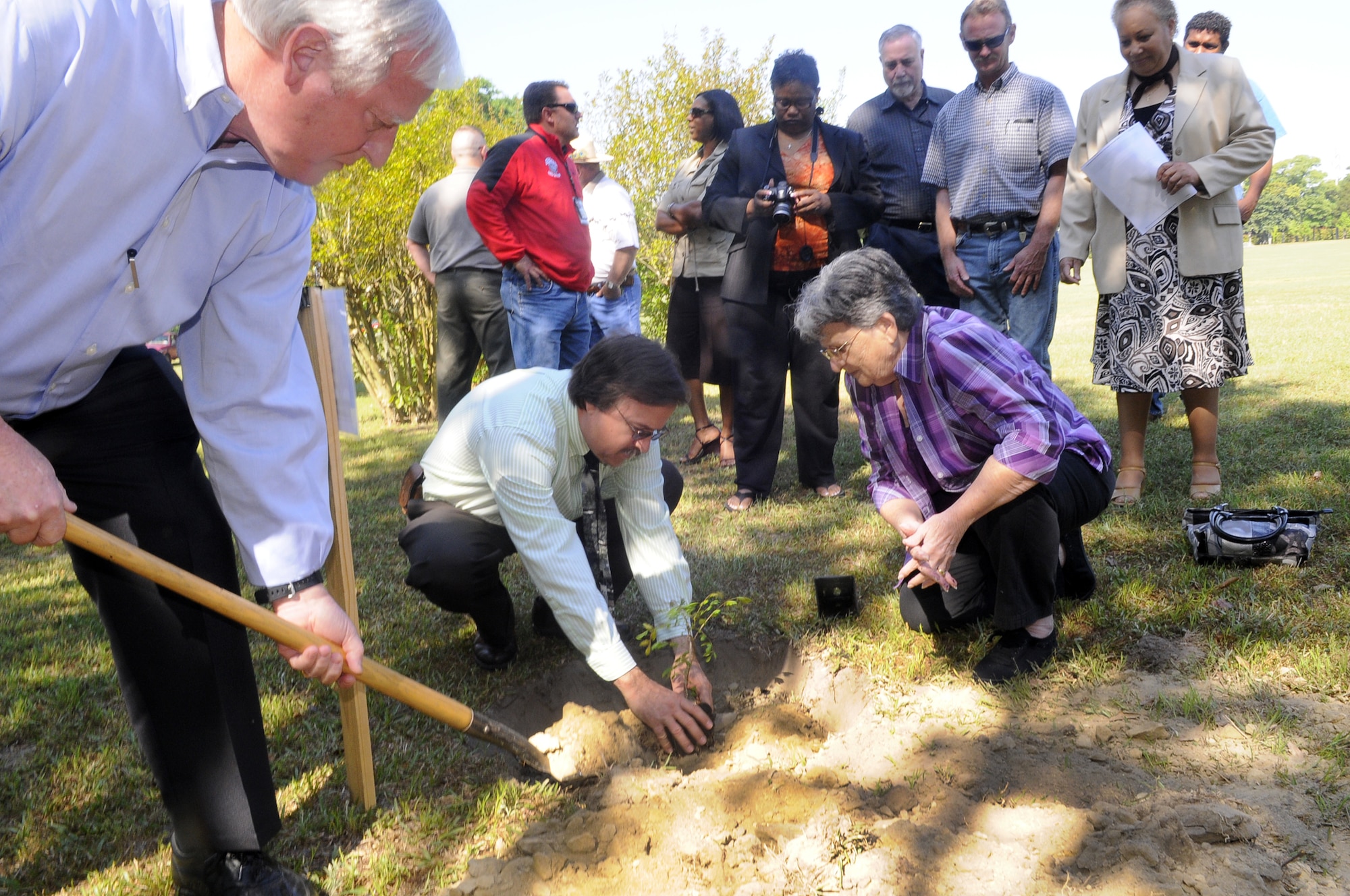 Joe Killebrew shovels soil while Bob Sargent assists Karen Swain to plant a Harriet Beecher Stowe Golden raintree in memory of her daughter Kim Baker. U. S. Air Force photo by Sue Sapp