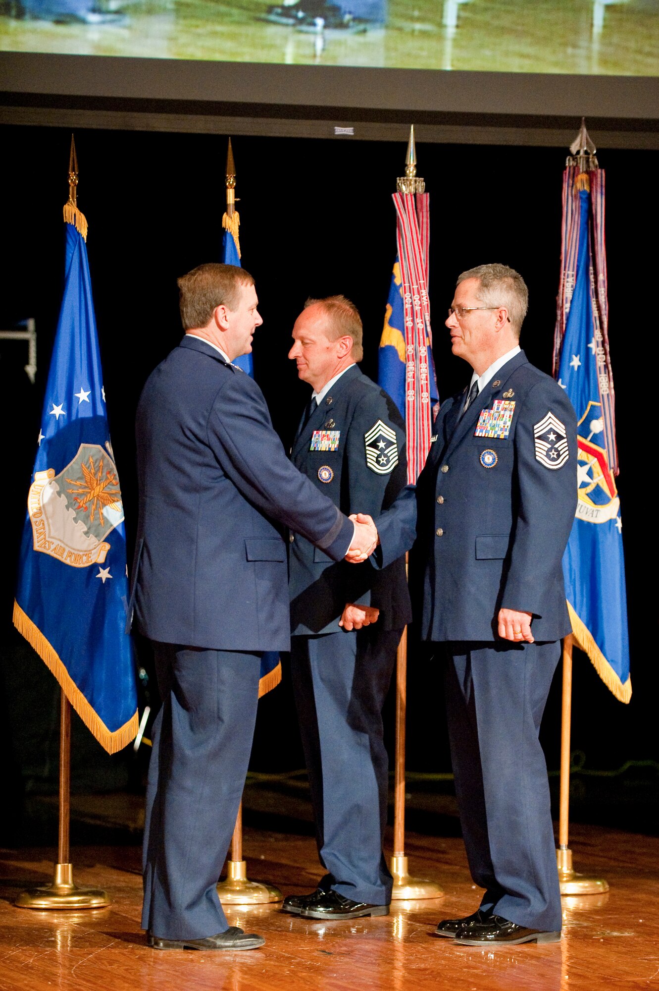 Kentucky's adjutant general, Maj. Gen. Edward Tonini (left), congratulates the new Kentucky Air National Guard state command chief master sergenat, Chief Master Sgt. James Smith (right), during a change-of-responsibility ceremony held April 17, 2010 at Louisville Male High School in Louisville, Ky. Chief Smith is replacing former Command Chief Master Sgt. Mark Grant (center), who is retiring from the Kentucky Air Guard after 30 years of service. (U.S. Air Force photo/Maj. Dale Greer)