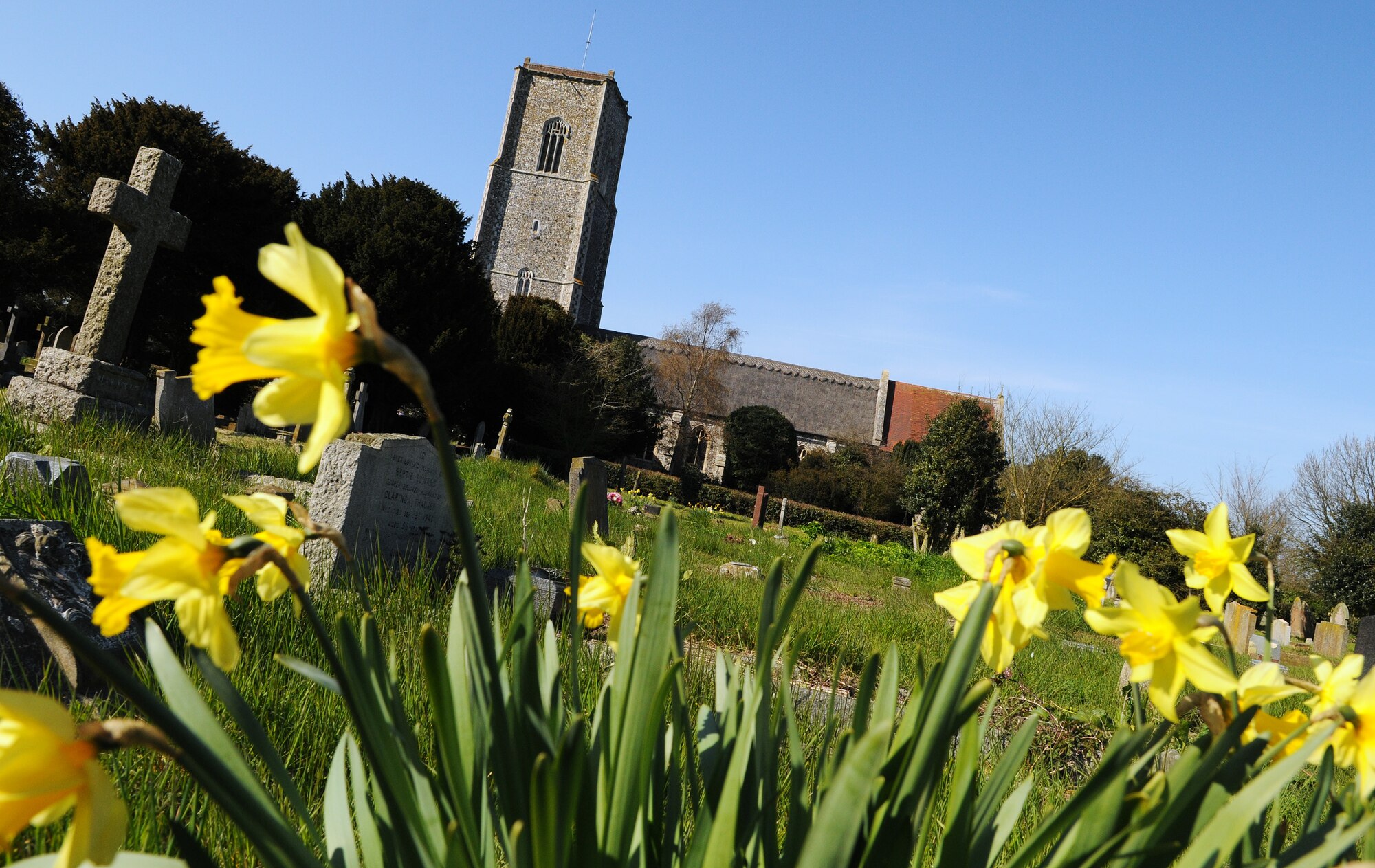 Kessingland, England -- Yellow flowers grow on the grounds of St. Edmund's Church in Kessingland near the village's war memorial. Twelve U.S. Air Force servicemembers were remembered in a memorial service April 22 to mark the 66th anniversary of the B24 Liberator 843 Repulser being downed by Axis fighter pilots. Rt. Rev. Graham James, Bishop of Norwich, officiated the service. (U.S. Air Force photo/Staff Sgt. Thomas Trower) 