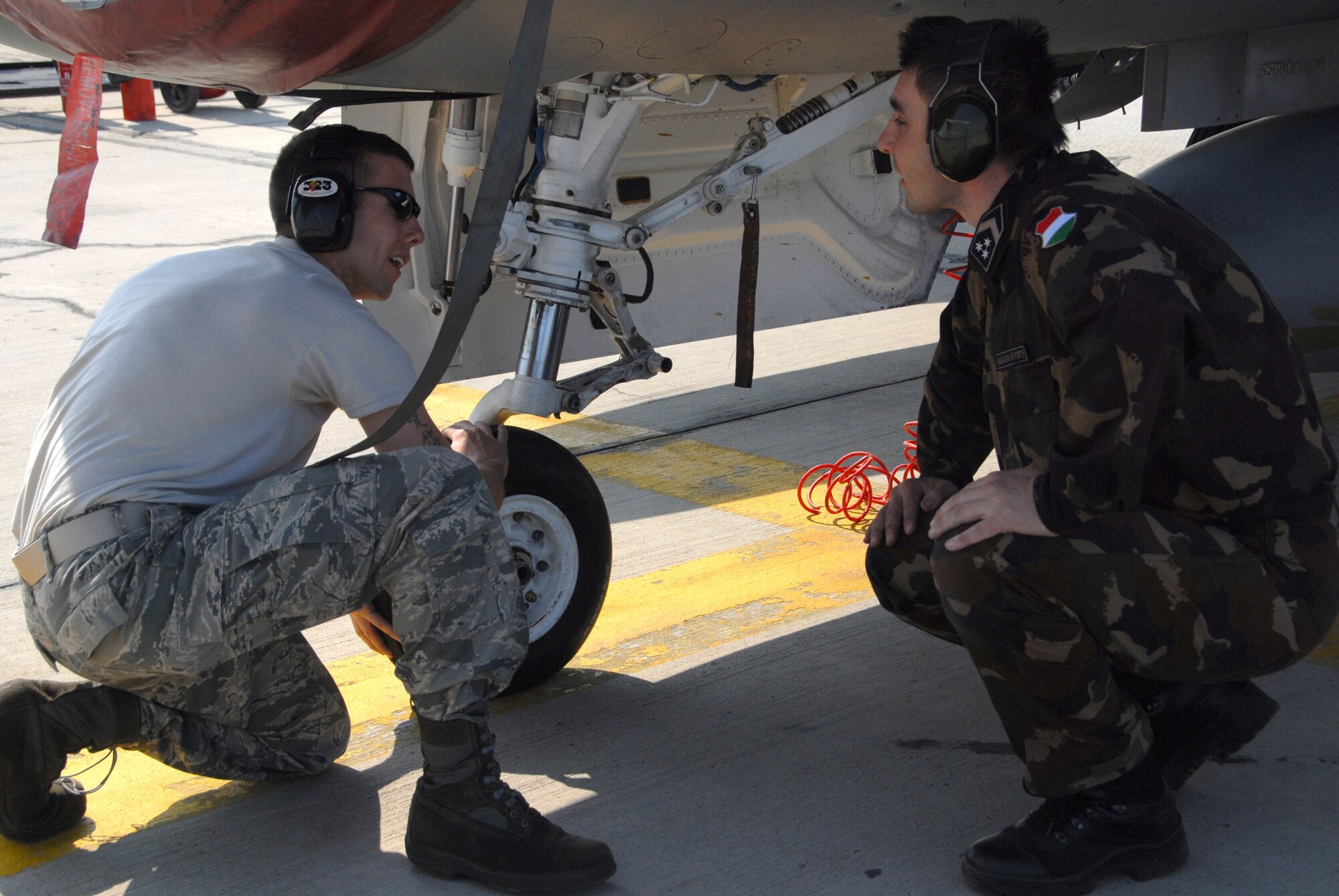 KECSKEMET, Hungary -- Staff Sgt. Brad Rowley, a 178th Fighter Wing crew chief, shows a Hungarian Air Force aircraft maintainer the nose landing gear on a F-16 Fighting Falcon during the Load Diffuser Exercise in Kecskemet, Hungary April 27. The exercise aims to sharpen the combat capabilities of the participating forces by conducting a 10 to 15 day flying program.