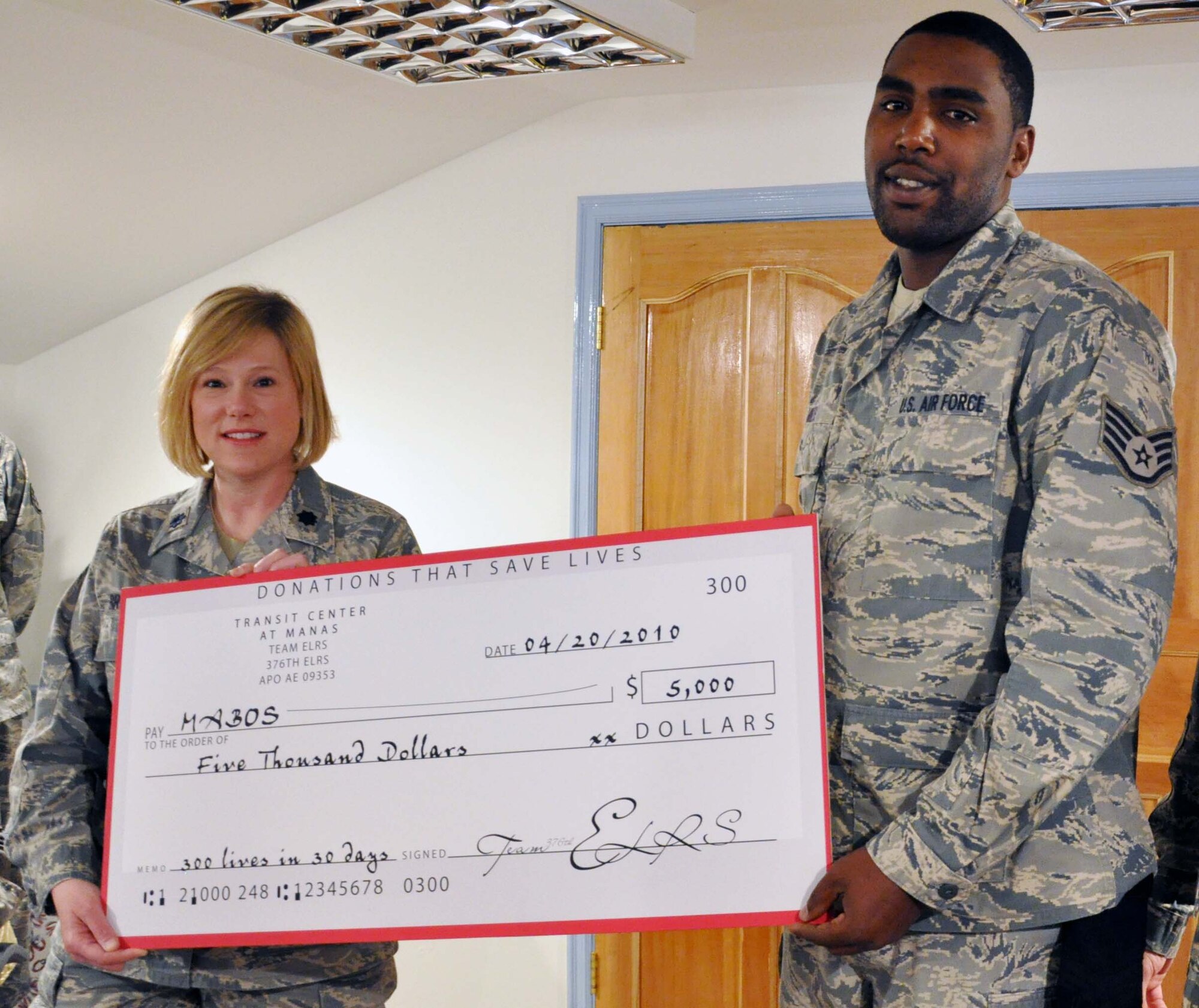 Staff Sgt. Eric Miles, a 376th Expeditionary Logistics Readiness Squadron vehicle operator, receives a check April 20, 2010, for $5,000 from his squadron commander, Lt. Col. Ann Brown, representing the amount of money the unit raised when he initiated a matching donation for local children's heart surgeries. Sergeant Miles' initial goal was to raise $500, and he offered to match squadron donations dollar-for-dollar up to $250. Because of his generosity, and the generosity of the Airmen in his unit, they raised enough to fund almost 10 heart surgeries for Kyrgyz children. (U.S. Air Force photo/Staff Sgt. Carolyn Viss)
