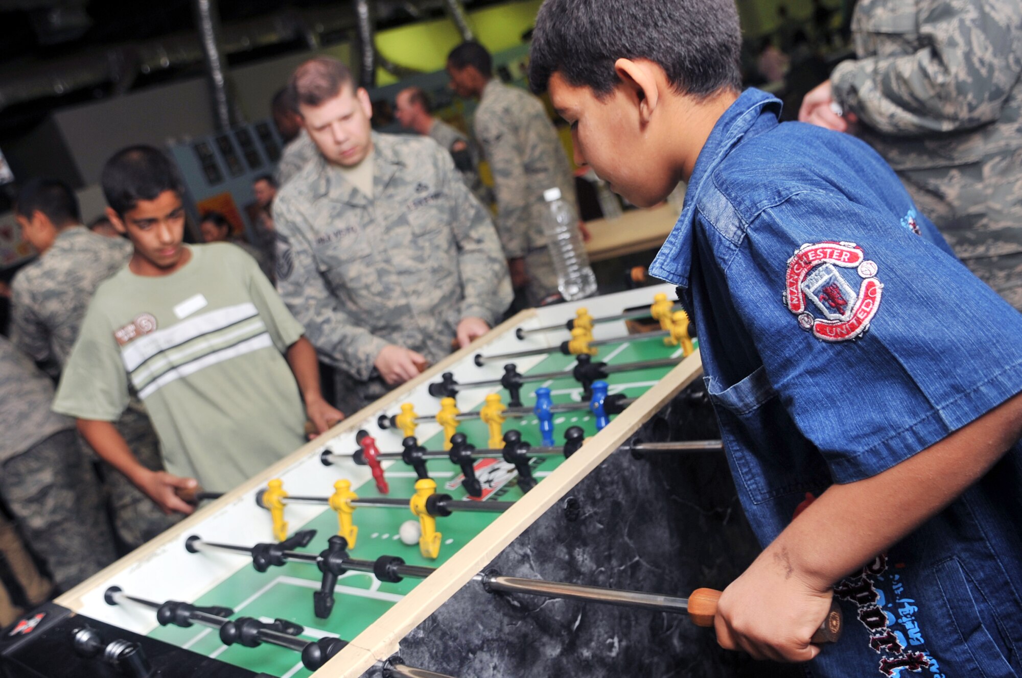Senior Master Sgt. James Haavisto, 332nd Expeditionary Operations Support Squadron weather flight NCO in charge, plays a game of foosball with two Iraqi boys during Iraqi Kids Day at Joint Base Balad, Iraq, April 24, 2010. This was the first Iraqi Kids Day of 2010 and it serves as part of the ongoing base effort to positively engage the local populace.  Thirty-four children from a local orphanage were bussed onto base to play games, share culture and to have a day of fun. (U.S. Air Force photo by Senior Airman Brittany Y. Bateman/Released)