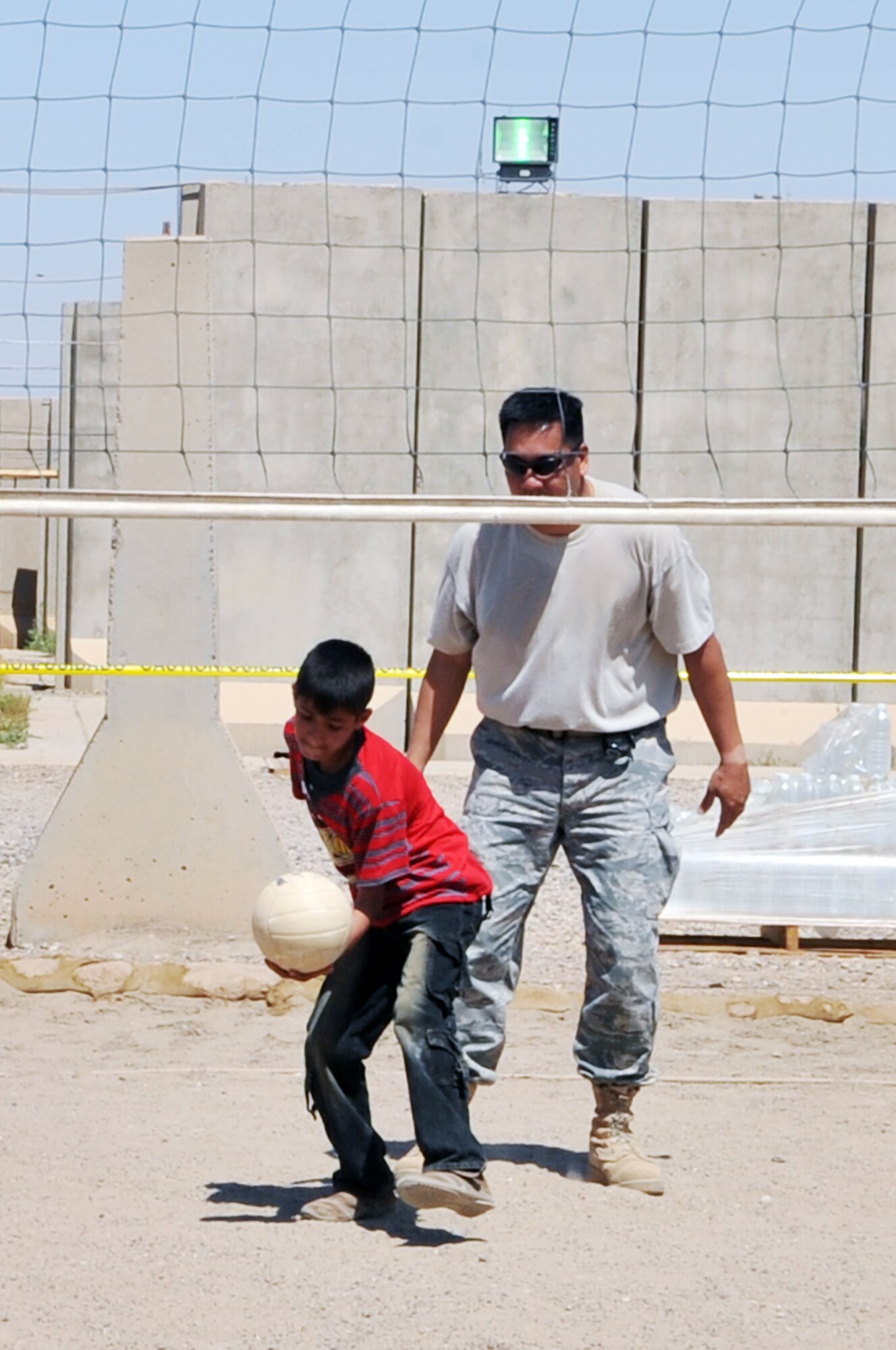 Tech. Sgt. Joseph Ferrer, 332nd Expeditionary Civil Engineer Squadron construction manager, plays volleyball with an Iraqi boy during Iraqi Kids Day at Joint Base Balad, Iraq, April 24, 2010. This was the first Iraqi Kids Day of 2010 and it serves as part of the ongoing base effort to positively engage the local populace.  Thirty-four children from a local orphanage were bussed onto base to play games, share culture and to have a day of fun. (U.S. Air Force photo by Senior Airman Brittany Y. Bateman/Released)