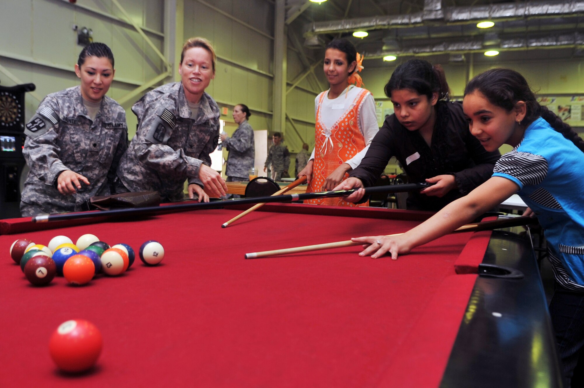 Army Col. Colleen Shull, 502nd Dental Company Area Support officer in charge, and Army Specialist Vanessa Infante, 502nd DCAS dental technician, play a game of billiards with some local children during Iraqi Kids Day at Joint Base Balad, Iraq, April 24, 2010. This was the first Iraqi Kids Day of 2010 and it serves as part of the ongoing base effort to positively engage the local populace.  Thirty-four children from a local orphanage were bussed onto base to play games, share culture and to have a day of fun. (U.S. Air Force photo by Senior Airman Brittany Y. Bateman/Released)