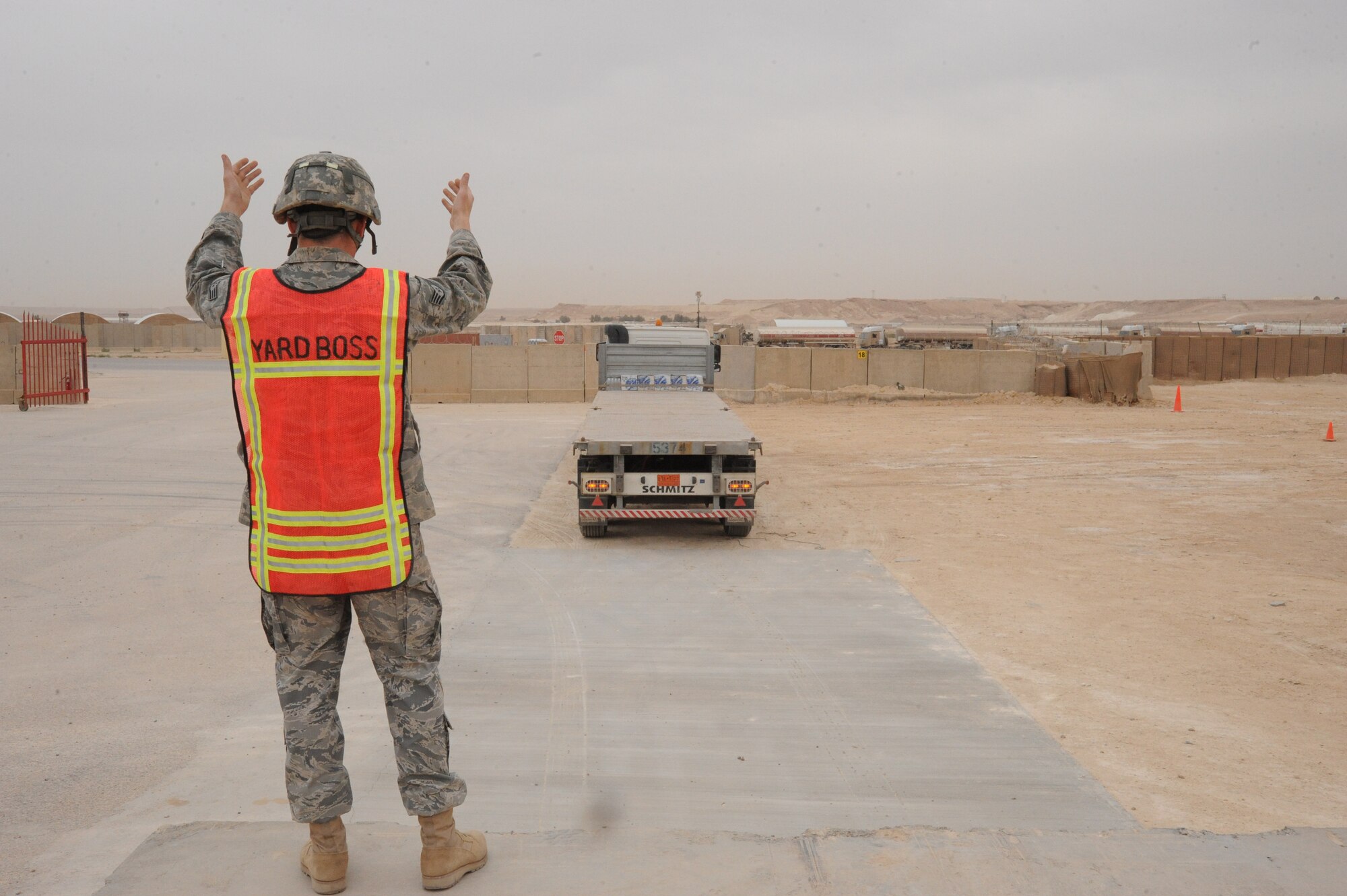 Air Force Staff Sgt. Matthew Burns, yard boss, 2/402nd Army Field Support Brigade, directs an eighteen wheeler where to back up before loading humvees whose final destination is Arifjan, Kuwait, as part of the Operation Iraqi Freedom drawdown, Al Asad Air Base, Iraq, April 17, 2010. The mission of the 2nd BN, 402 AFSB Redistribution Property Assistance Team is to meet the presidential intent to facilitate the expedient turn-in of all excess Class VII Theater Provided Equipment, improve property accountability of retrograding equipment from Iraq and enable asset visibility of the received equipment during transit to Source of Repair or Operation Enduring Freedom. (U.S. Air Force photo/Master Sgt. Trish Bunting/Released)