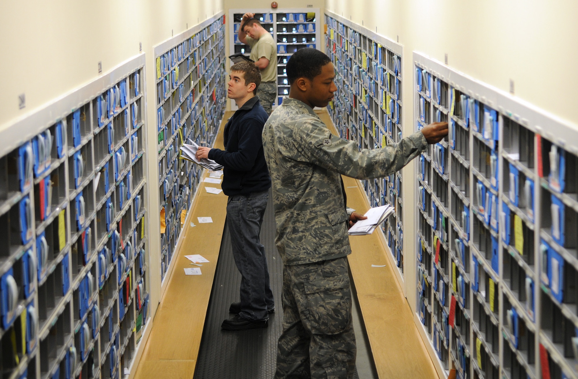 RAF MILDENHALL, England -- Amn. Landon Young-Jackson, volunteer (front), Richard Oot and Senior Airman Cory Jones, 100th Communications Squadron postal clerks, sort mail into individual mail boxes at the RAF Mildenhall Post Office April 26. Post Office employees were trying to clear through a backlog of mail that had arrived after flight restrictions were lifted following the eruption an volcano in Iceland . (U.S. Air Force photo/Staff Sgt. Thomas Trower)