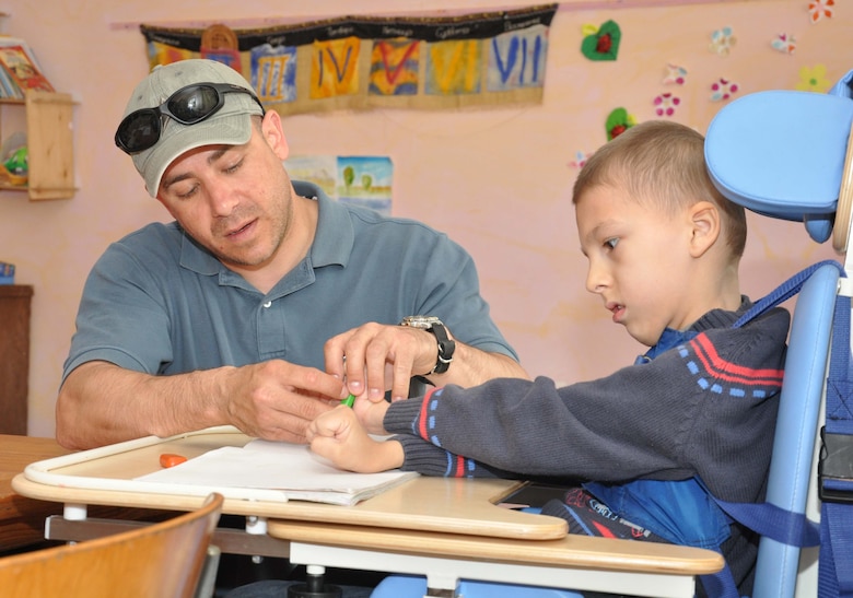 A father interacting with his son who is drawing a picture. He could be portraying the style of teacher-counselor or athletic coach^[[Image](https://www.afcent.af.mil/News/Article/220433/tc-manas-helps-nadjeshda-support-disabled-children/) by [U.S. Air Forces Central Command](https://www.afcent.af.mil/) is in the public domain]