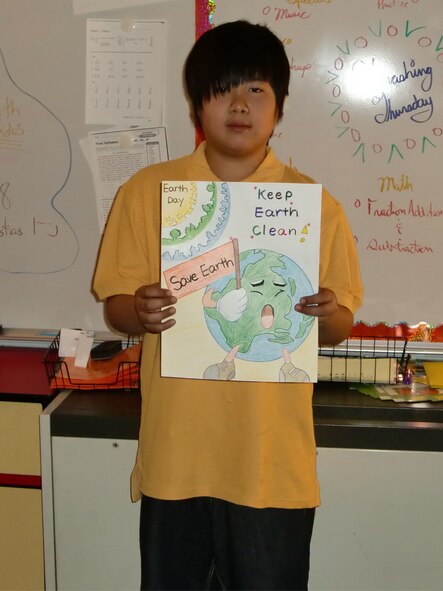 Sung June DeAngelo, a fifth-grade student at Osan American Elementary School, displays his winning entry in the Earth Day poster contest. The 51st Civil Engineer Squadron sponsored the contest and selected the top three drawings out of all submissions received from base schools by April 19. Each winner received $50 and a 51 CES coin. (Courtesy photo)