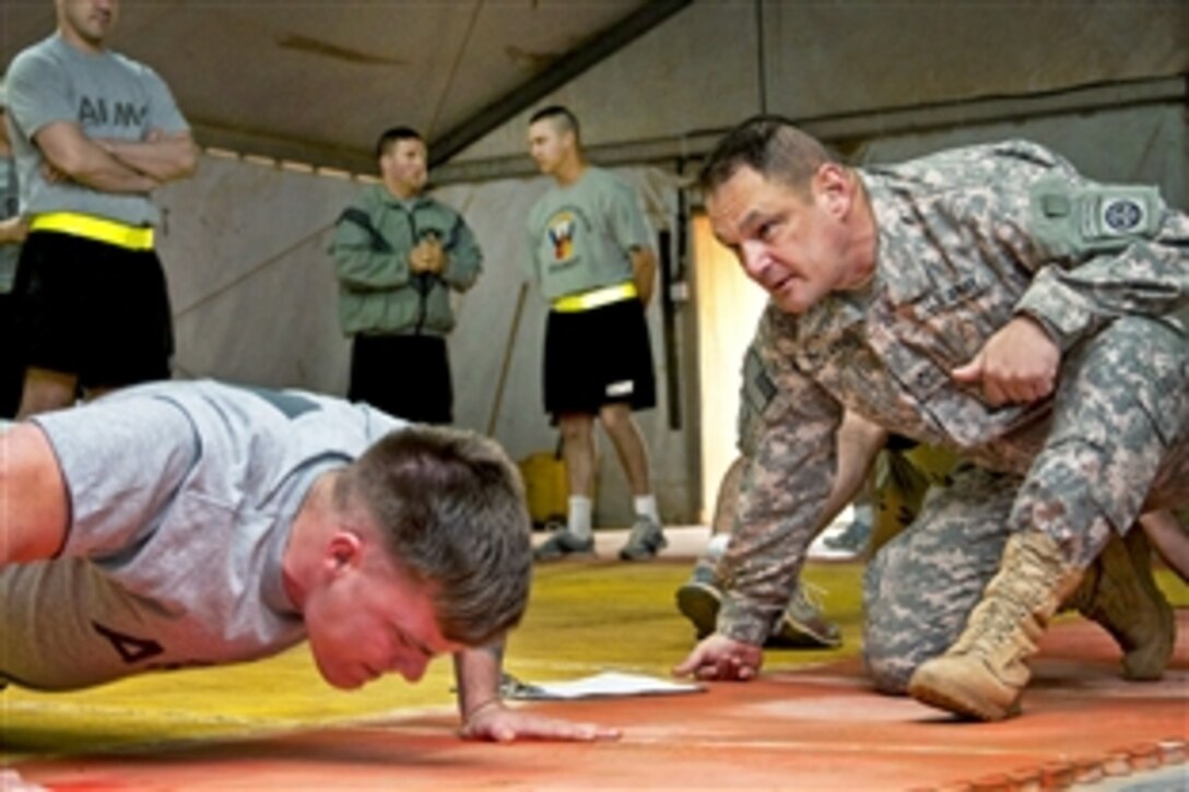 U.S. Army Staff Sgt. Christopher Bower, left, grades pushups for Spc. Andrew Duncan, during an Army physical fitness test on Camp Ramadi, Iraq, April 17, 2010. Bower and Duncan are assigned to the 82nd Airborne Division's Headquarters Company, 1st Brigade Combat Team, Advise and Assist Brigade. Fitness is one criteria soldiers must meet to enroll in the Noncommissioned Officers Education System schools.