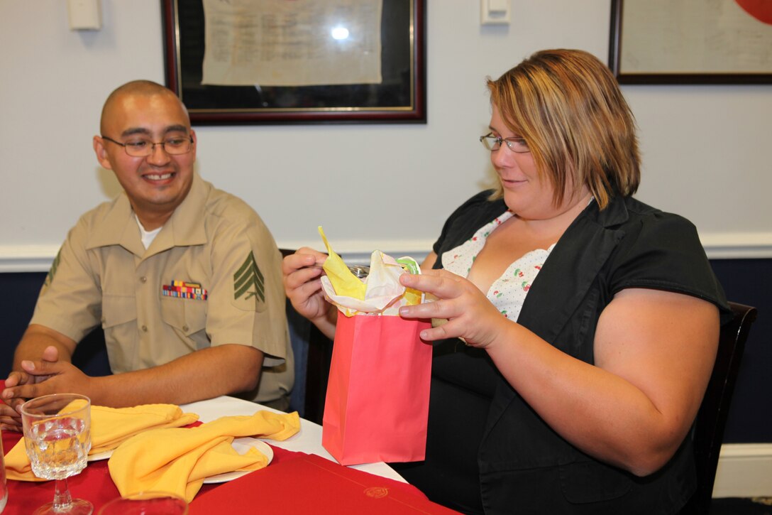 Sgt. Jonathan Flowers (left), a food service warehouse clerk with Headquarters and Support Battalion, Marine Corps Base Camp Lejeune, watches his wife, Tiffanie, a family readiness assistant, open a gift bag  she received during the Volunteer Appreciation Dinner at the Paradise Point Officers’ Club aboard MCB Camp Lejeune, April 29.  The dinner recognized volunteers who make it their mission to offer strong support to military families.