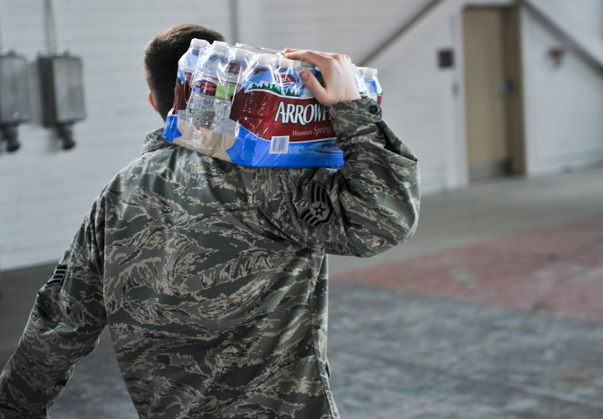 ELMENDORF AIR FORCE BASE, Alaska – An Airman walks out of Hangar 5 with a case of water April 29. Due to recent elevated levels of fluoride in water on Elmendorf and Fort Richardson, the base has been supplying water at Hangar 5. (Air Force photo by Airman 1st Class Christopher Gross)