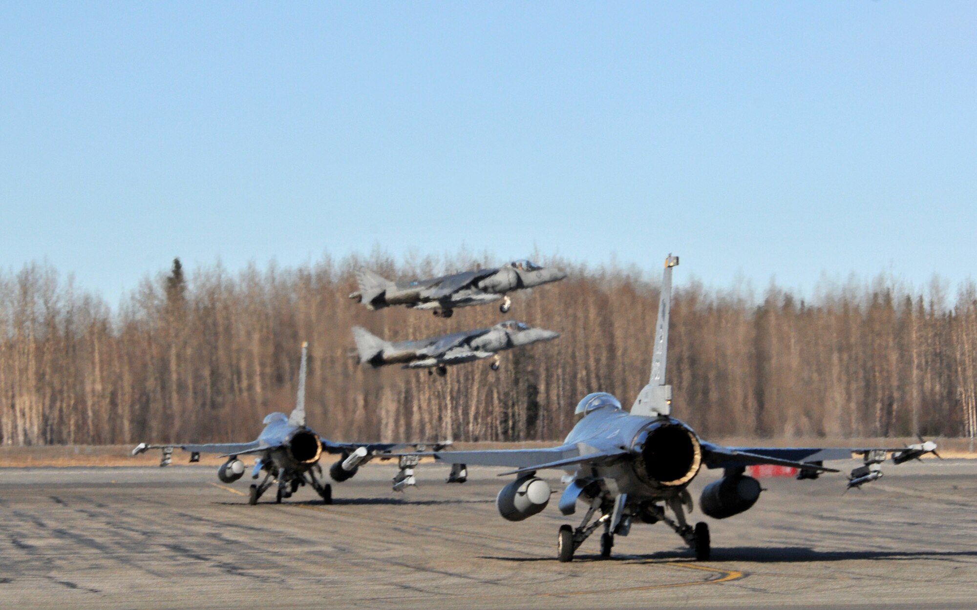 Two Marine AV-8B Harriers from VMA 211, Marine Corps Air Station, Yuma, Arizona, take off as two F-16 Fighting Falcons from the 8th Fighter Wing, Kunsan Air Base, Republic of Korea, during Red Flag-Alaska at Eielson Air Force Base, Alaska, April 21. Red Flag-Alaska is a 10-day field training exercise that provides joint offensive counter-air, interdiction, close air support, and large force employment training in a simulated combat environment. (U.S. Air Force photo/Capt. Shannon Collins)