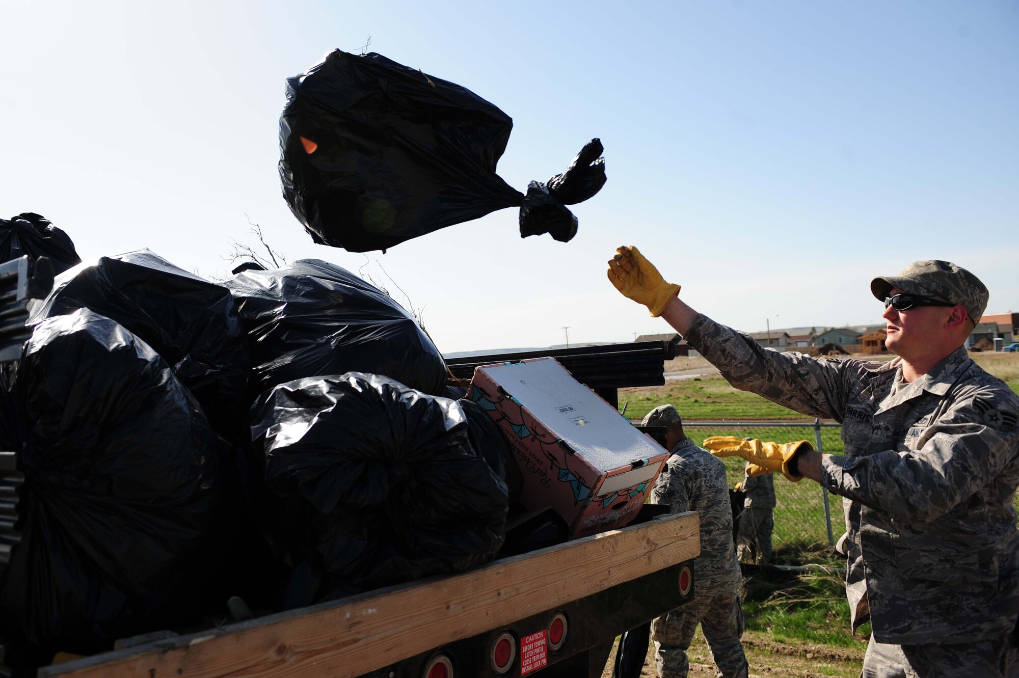 ELLSWORTH AIR FORCE BASE, S.D. - Senior Airman John Parris, 28th Civil Engineer Squadron heating, ventilation and air conditioning repair journeyman, throws a bag of trash into a truck for disposal during a base cleanup, April 28.  More than 20 Airmen volunteered for the cleanup, saving the Air Force $4,000 in contracting costs. (U.S. Air Force photo/Airman 1st Class Corey Hook)