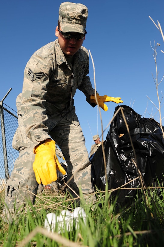 ELLSWORTH AIR FORCE BASE, S.D. -- Senior Airman Christopher Harris, 28th Civil Engineer Squadron heating, ventilation and air conditioning repair journeyman, picks up trash during a base cleanup, April 28.  Airmen volunteered to help the base by bagging litter and properly disposing of it. (U.S. Air Force photo/Airman 1st Class Corey Hook)