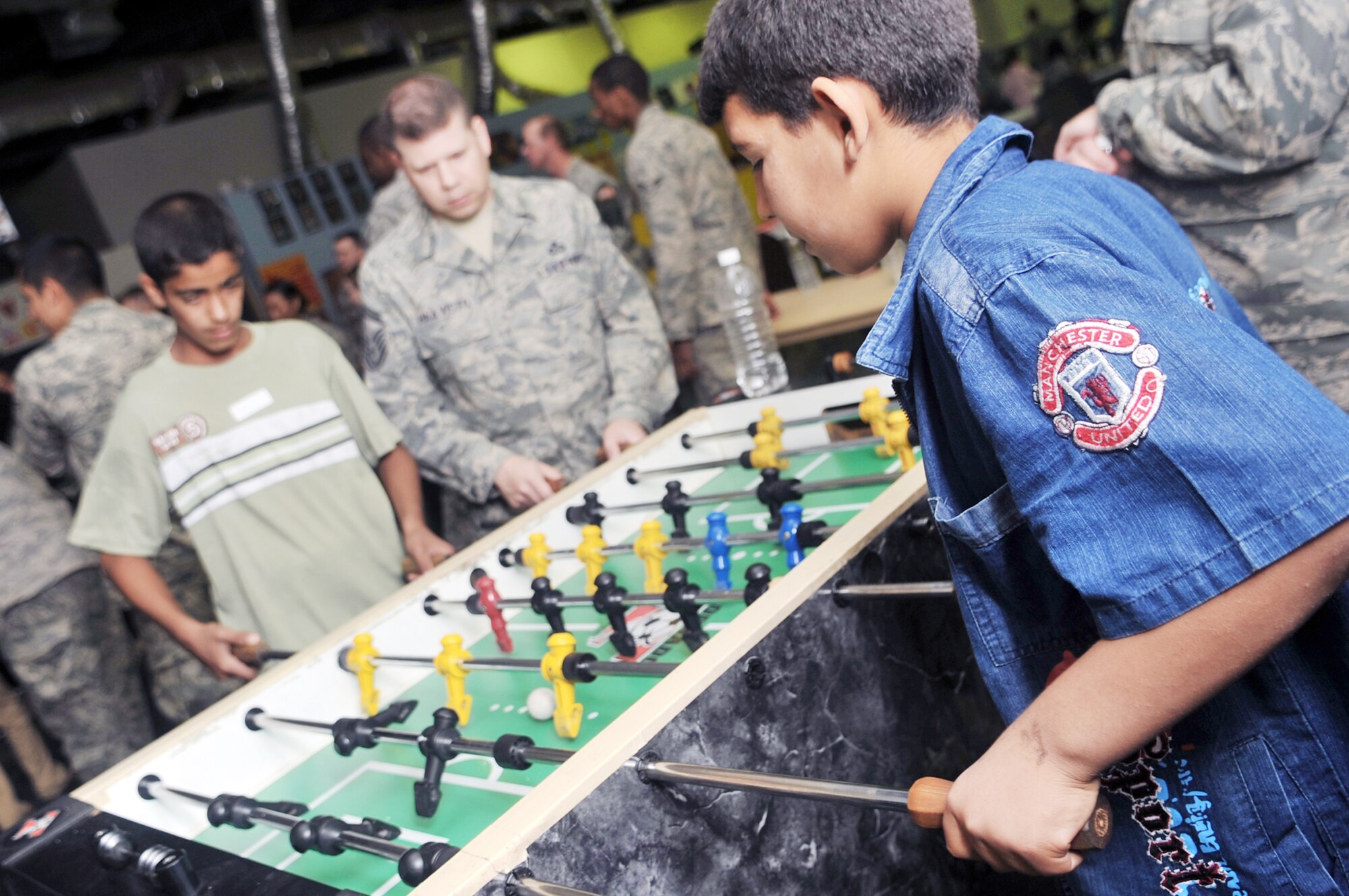 Senior Master Sgt. James Haavisto plays a game of foosball with two Iraqi boys during Iraqi Kids Day April 24, 2010, at Joint Base Balad, Iraq. Sergeant Haavisto is a 332nd Expeditionary Operations Support Squadron NCO in charge of the weather flight. (U.S. Air Force photo/Senior Airman Brittany Y. Bateman)