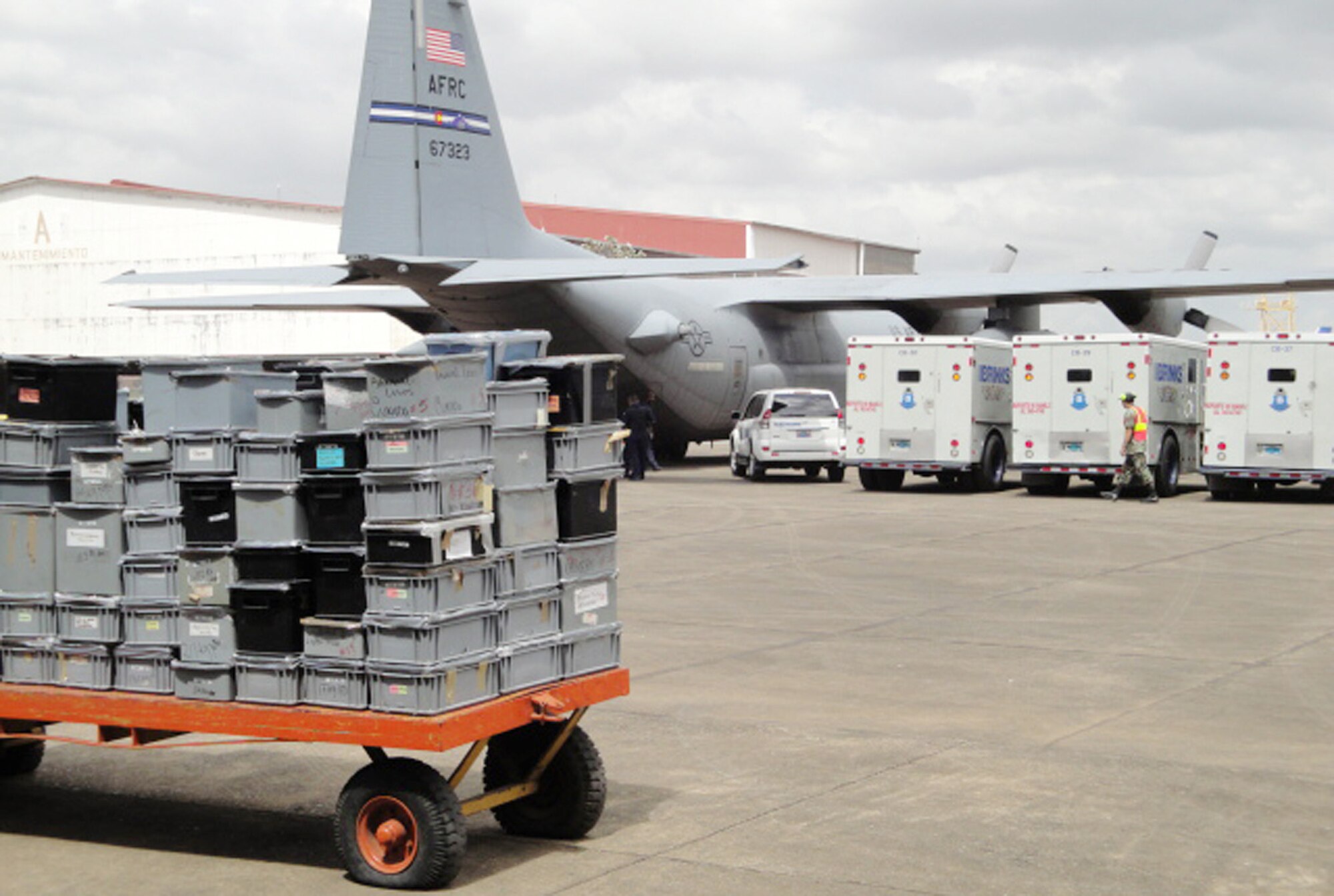 Several armored trucks full of seized gold, silver and jewels wait to be unloaded as security personnel protect a 302nd Airlift Wing C-130 April 8, 2010, at an air base in Panama. The seized assets were part of a joint Panama-U.S. investigation into an international drug money laundering scheme in the Central American country. Airmen from the Air Force Reserve's 302nd AW were tasked with flying the seized metals and jewels back to the United States for further processing by Department of Justice agencies. (Courtesy photo/Drug Enforcement Agency)