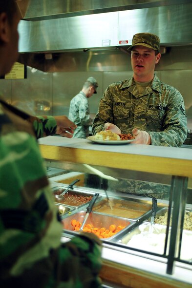ELLSWORTH AIR FORCE BASE, S.D.- Airman 1st Class Reece Audette, 28th Force Support Squadron food service apprentice, serves food to an Airman at the Bandit Inn Dining Facility, April 27.  For Airmen living in the base dormitories, the dining facility is often the start and end to their day.  (U.S. Air Force photo/Airman 1st Class Corey Hook)