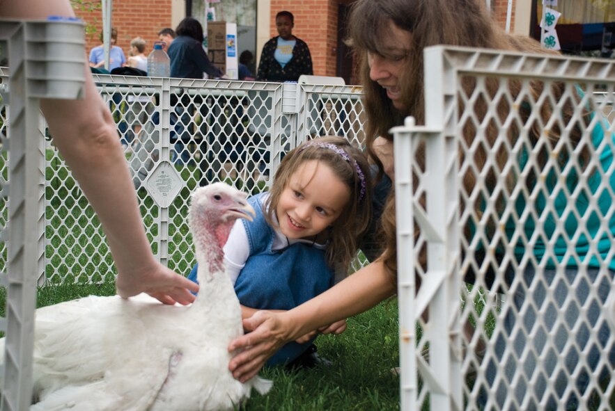 SCOTT AIR FORCE BASE, Ill. -- Sarah Morris, 5, takes a close look at a white turkey with Teresa Fehrenz, the mother of another 4-H member.  Sarah was at the Skill-a-thon with her dad, Master Sgt. Anthony Morris. (U.S. Air Force Photo by Steve Berry) 