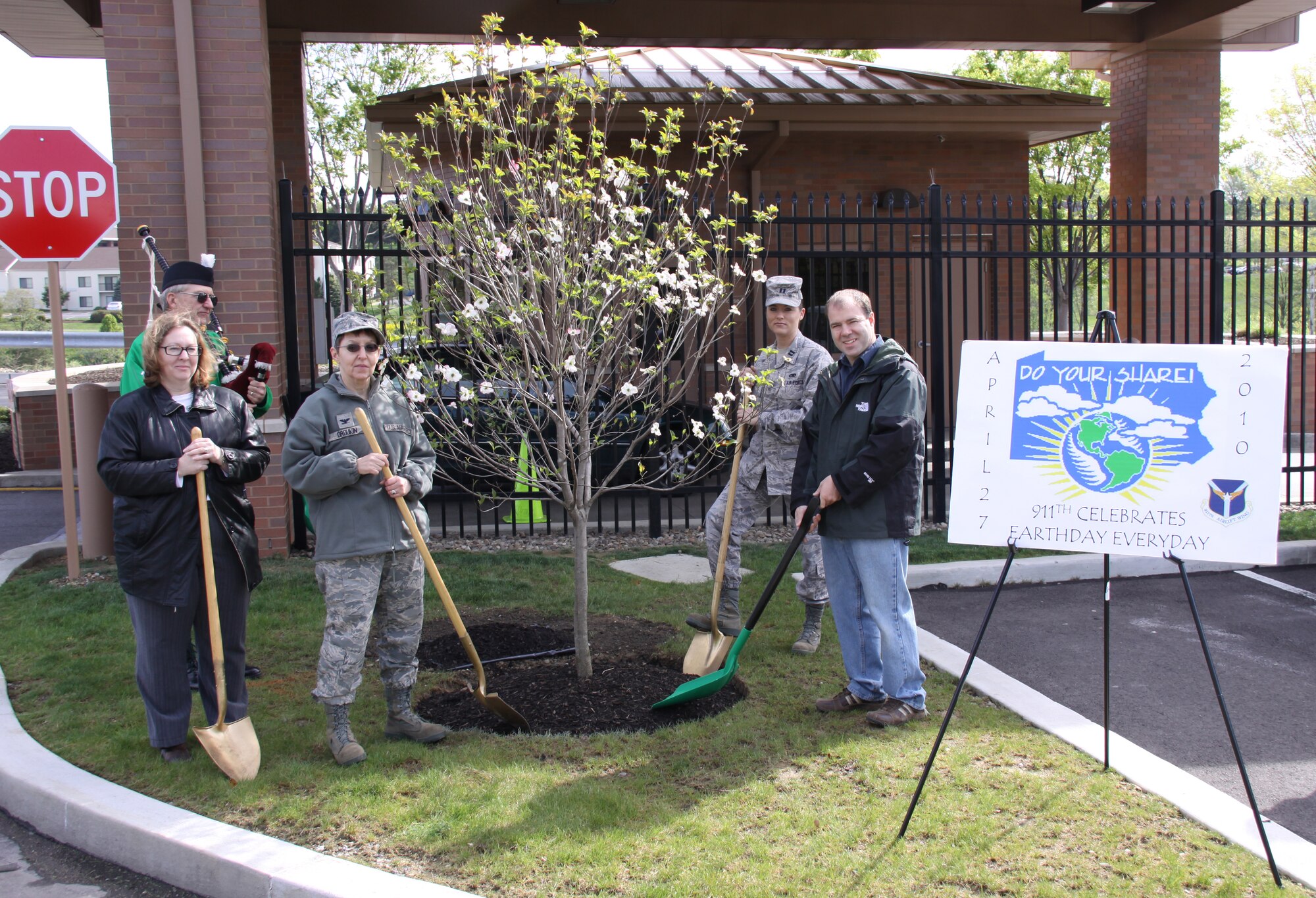 The 911th Airlift Wing begins its Earth Day 2010 celebration with an annual tree planting, held here April 27.  Ms. Melody Stewart-Markley, Civilian Personnel administrative assistant; Col. Rebecca Oroukin, 911th Mission Support Group commander; Capt. Misty Bartley, 911th AW executive officer; and Mr. Brian Keenan, 911th Civil Engineering Squadron engineering technician, man the shovels while Mr. Robert Clifford plays American patriotic songs on the bagpipe.  This was the 15th year for the base to celebrate the event. Other activities included a base clean up, a presentation on composting with and without worms, as well as how to save water by using a rain barrel.