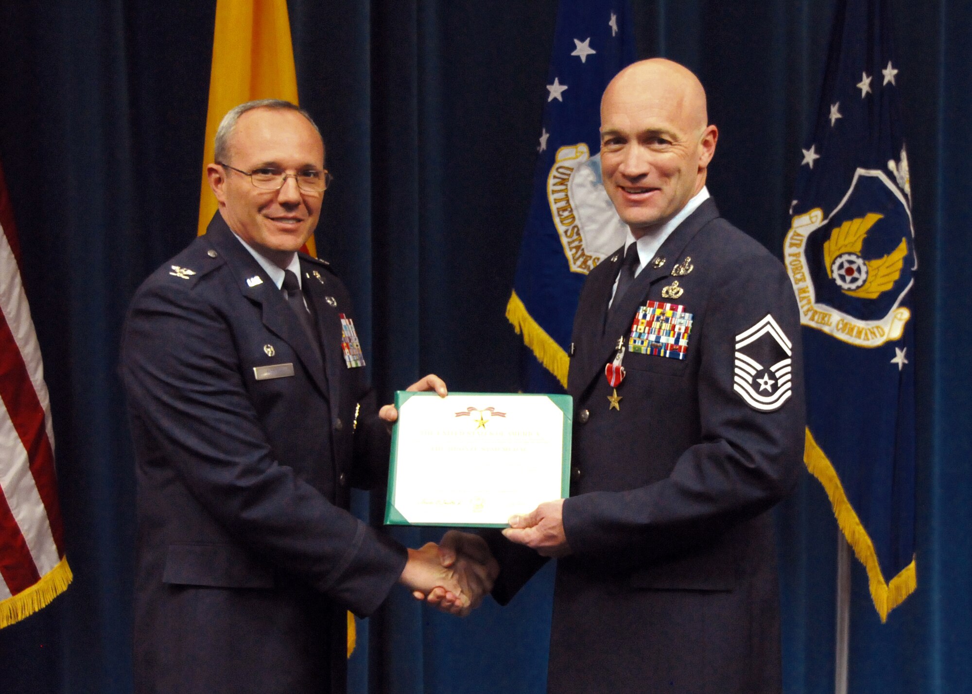 Col. Robert Maness, 377th ABW Commander, presents Senior Master Sgt. Brett Rogers, 377th MSG/EOD with the Bronze Star at a ceremony at the Wing Presentation Center on April 26th.  U.S. Air Force Photo by Dennis Carlson