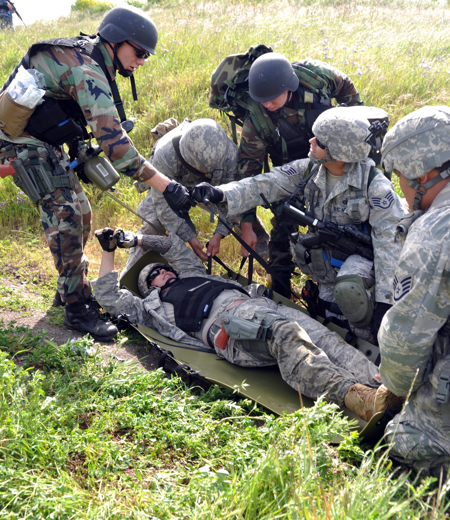 Travis security forces and Navy Master of Arms (Navy police), help an injured Airman onto a stretcher during an exercise at Camp Park Reserve Force Training Area in Dublin, Ca. (U.S. Air Force photo/Airman 1st Class Michael Battles)