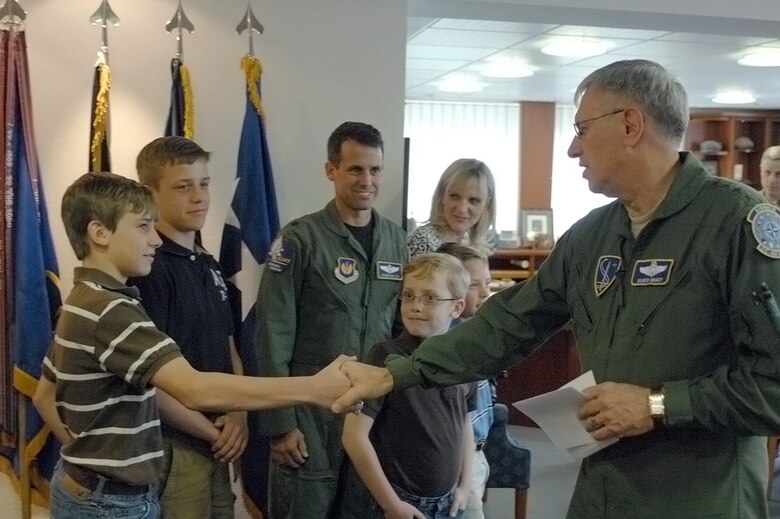 Gen. Roger Brady shakes hands with Hunter Koltes, 13, before announcing Hunter won the Year of the Air Force Family video competition, April 21, 2010, at Ramstein Air Force Base, Germany. General Brady congratulated Hunter and presented him a $2,000 gift check toward the purchase of a computer and video camera and a commander's coin for his tribute video called, "Life of a Military Brat." General Brady is the U.S. Air Forces in Europe commander. (U.S. Air Force photo/Master Sgt. Corey Clements)
