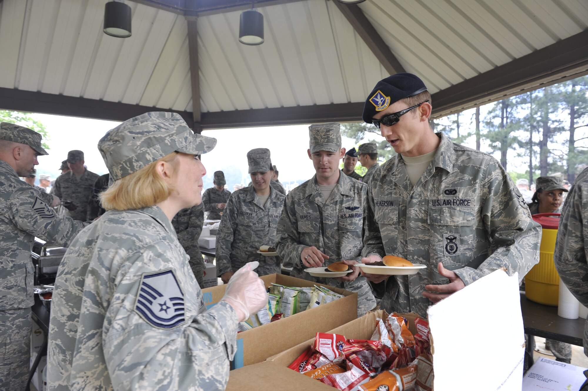 Master Sgt. Kimberly Knott, 19th Contracting Squadron, hands Senior Airman John Wilkerson, 19th Security Forces Squadron, a bag of chips during the commander's all call held April 27 at the War fit Track. A burger burn was held in appreciation for the hard work put forth by 19th Airlift Wing members that led to an overall excellent rating for the unit compliance inspection. (U.S. Air Force photo by Senior Airman Christine Clark)
