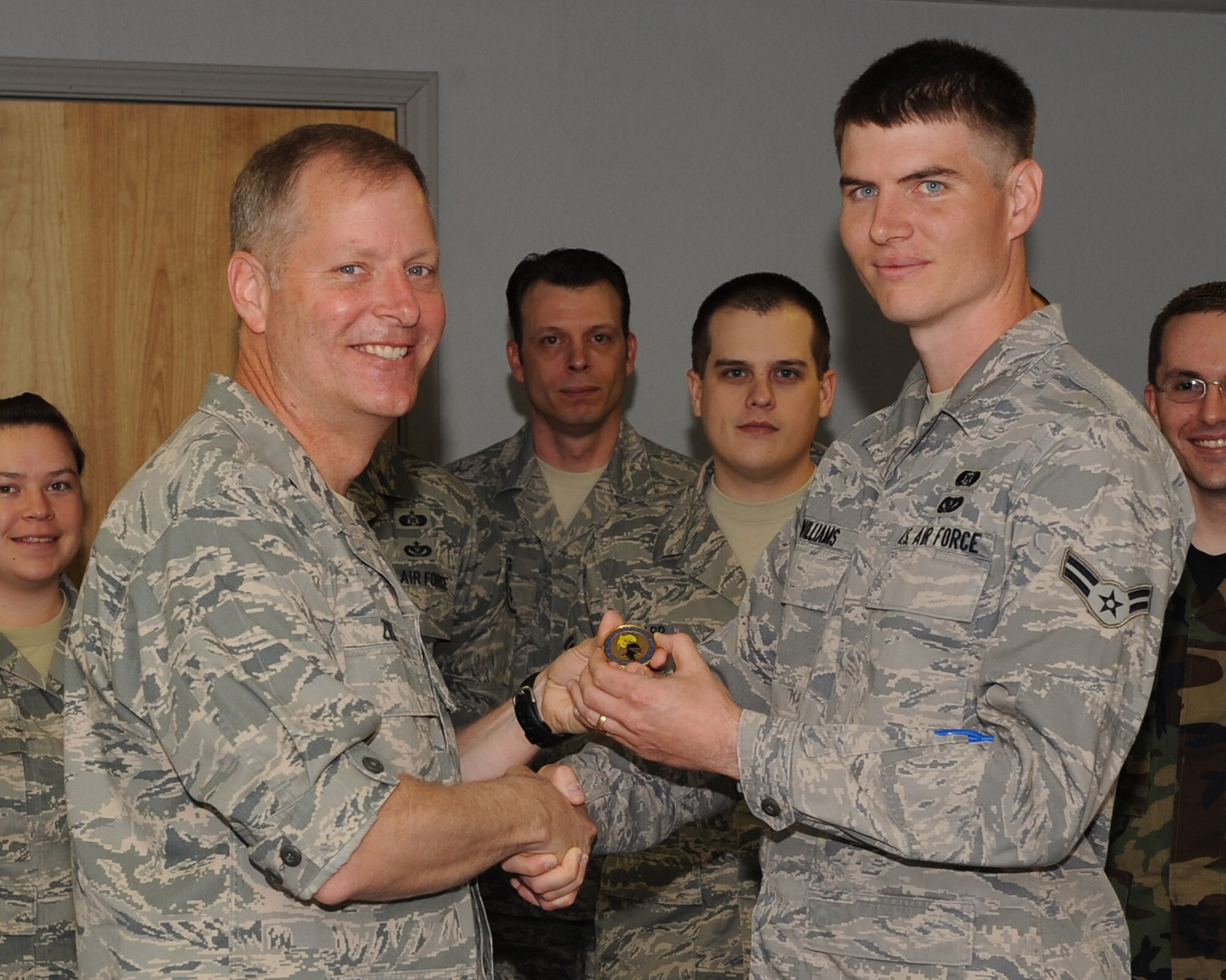 Col. Michael Zick, 19th Airlift Wing vice commander, presents a coin to Airman 1st Class Nathan Williams, 19th Civil Engineer Squadron readiness apprentice, April 27 for his selection as the Combat Airlifter of the Week. Airman Williams executed wing-wide shelter-in-place programs and built 86 shelter kits for 35 facilities. (U.S. Air Force photo by Staff Sgt. Chad Chisolm)