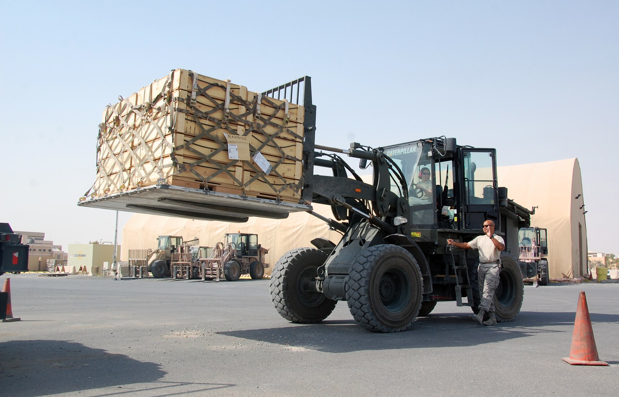 U.S. Air Force Tech. Sgt. Clarence Marshall spots Tech. Sgt. Patricia Lapp as she prepares to load a 463L cargo pallet onto a 60K loader April 27, 2010 at an undisclosed location in Southwest Asia. Both Sergeant Marshall and Sergeant Lapp are deployed with the 386th Expeditionary Logistics Readiness Squadron Aerial Port team, whose mission is to move personnel and cargo in and out of the U.S. Central Command area of responsibility. (U.S. Air Force photo by Tech. Sgt. Lindsey Maurice/Released)