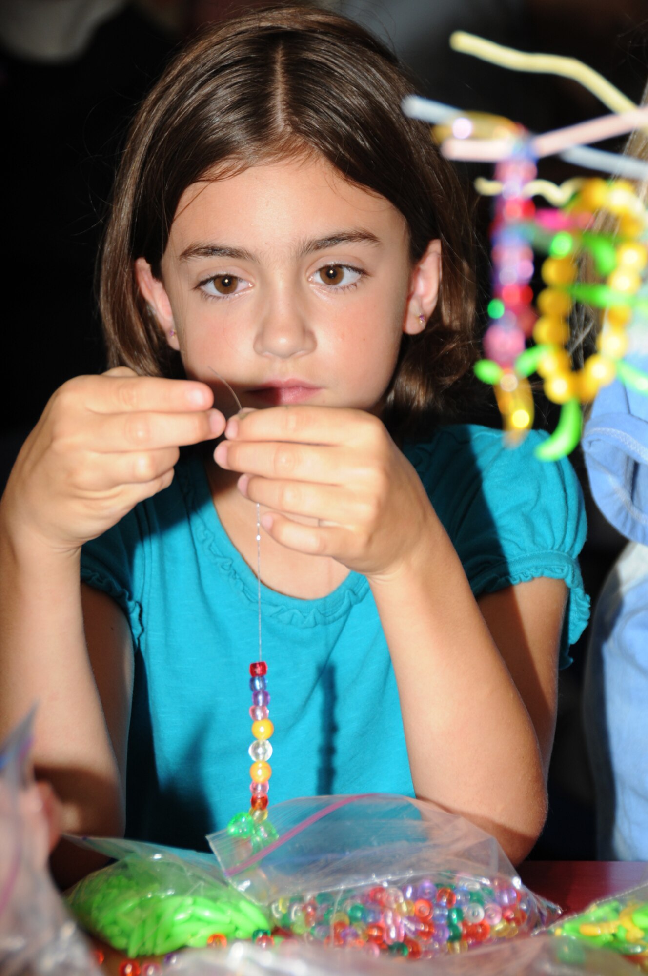 Ashley Linville, 8, daughter of Tech. Sgt. Jeffrey and Heather Lin-ville, 81st Training Wing, strings beads for a brace-let.  Her dad is deployed.  (U.S. Air Force photo by Kemberly Groue)