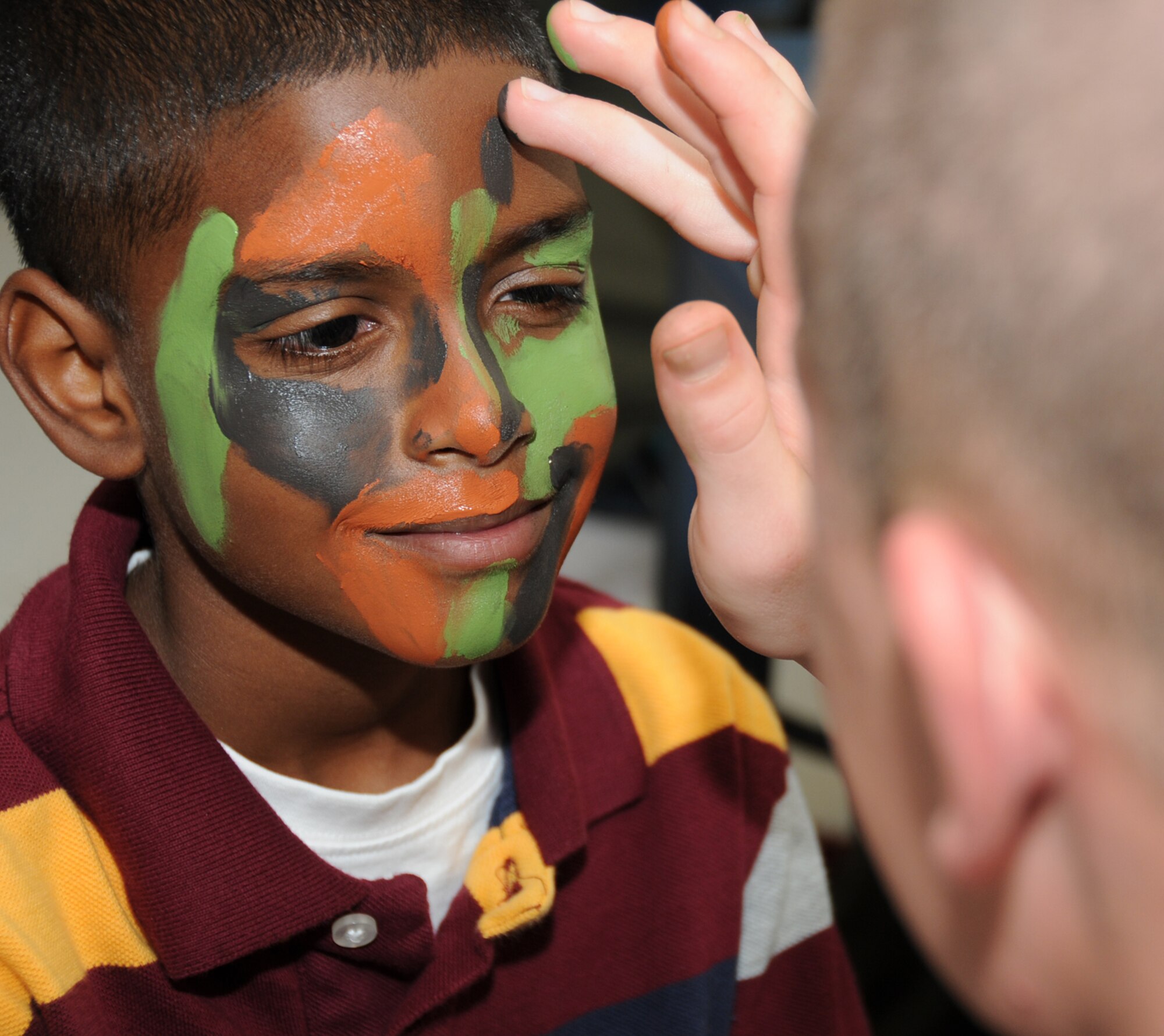 Quentin Gray, 9, son of Master Sgt. Rodney and Kimberly Gray, has his face painted by Pfc. Michael Gable, Keesler Marine Corps Detachment, at Saturday’s Child Pride Day at the youth center.  Sergeant Gray is stationed at Osan Air Base, Korea.  (U.S. Air Force photo by Kemberly Groue)