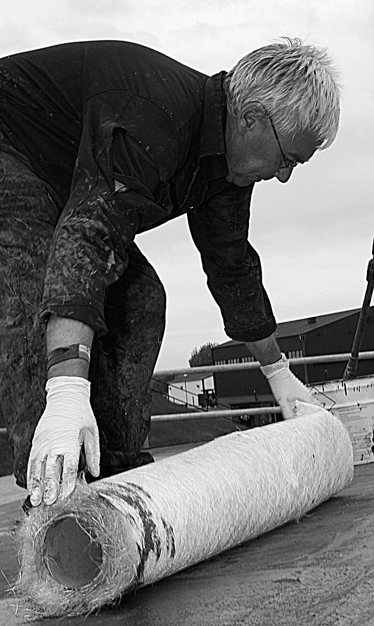RAF MILDENHALL, England – Tom Farrington, a local contractor, unrolls fiberglass fabric to seal the roof of a strorage facility near Building 645 April 29.  The fabric is bonded to the roof before a final sealer is applied.  (U.S. Air Force photo/Staff Sgt. Christopher L. Ingersoll)