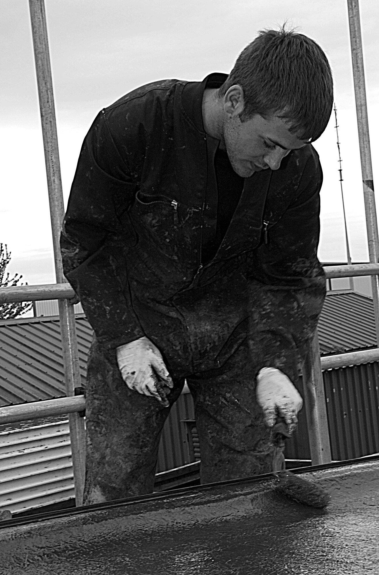 RAF MILDENHALL, England – Andy Carstairs, contractor, touches up undercoating on the roof of a storage facility near Building 645 April 29.  The undercoating consists of a liquid compound that merges with a fiberglass fabric to seal any leaks.  (U.S. Air Force photo/Staff Sgt. Christopher L. Ingersoll)