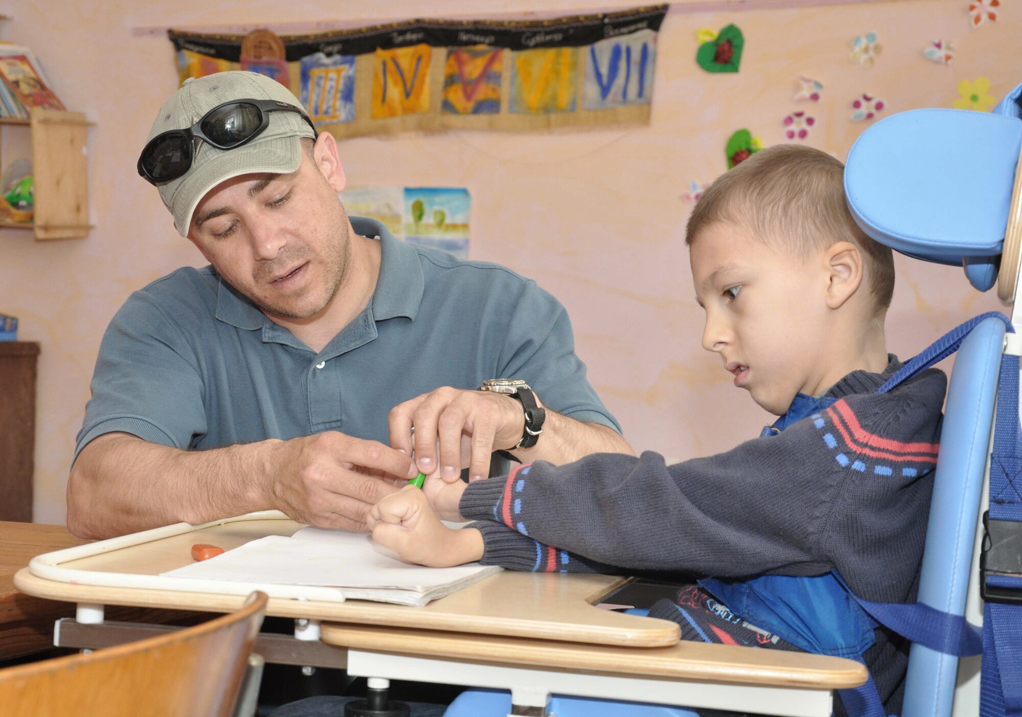 Master Sgt. Jeff Villemarette helps a boy with cerebral palsy color during a special education class April 27, 2010, at the Nadjeshda Children's Center in Kyrgyzstan. Nadjeshda is home for 60 children and teenagers who are disabled in different ways. Sergeant Villemarette is assigned to the Transit Center at Manas. (U.S. Air Force photo/Staff Sgt. Carolyn Viss)