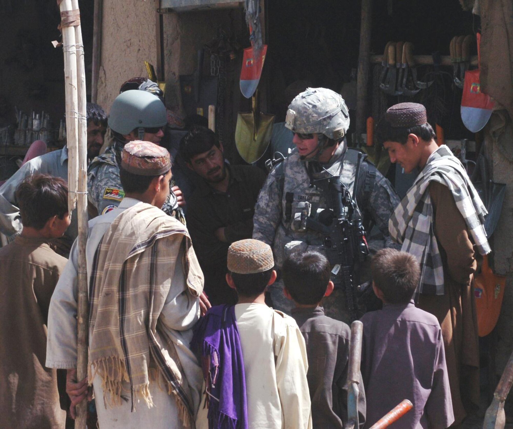 First Lt. Addison Taylor, production officer for the agriculture section of the Arkansas National Guard's Agriculture Development Team in Zabul Province, stops outside of a farm supply store to explain the team's farming education mission to youngsters during its visit to the Qalat City Bazaar on April 29, 2010. The 188th Fighter Wing deployed three unit members with the ADT, including Maintenance Squadron commander, Lt. Col. David Sheely, who is the team leader for the ADT's agricultural specialists. (U.S. Air Force photo by Lt. Col. Keith Moore/Arkansas National Guard Public Affairs)
