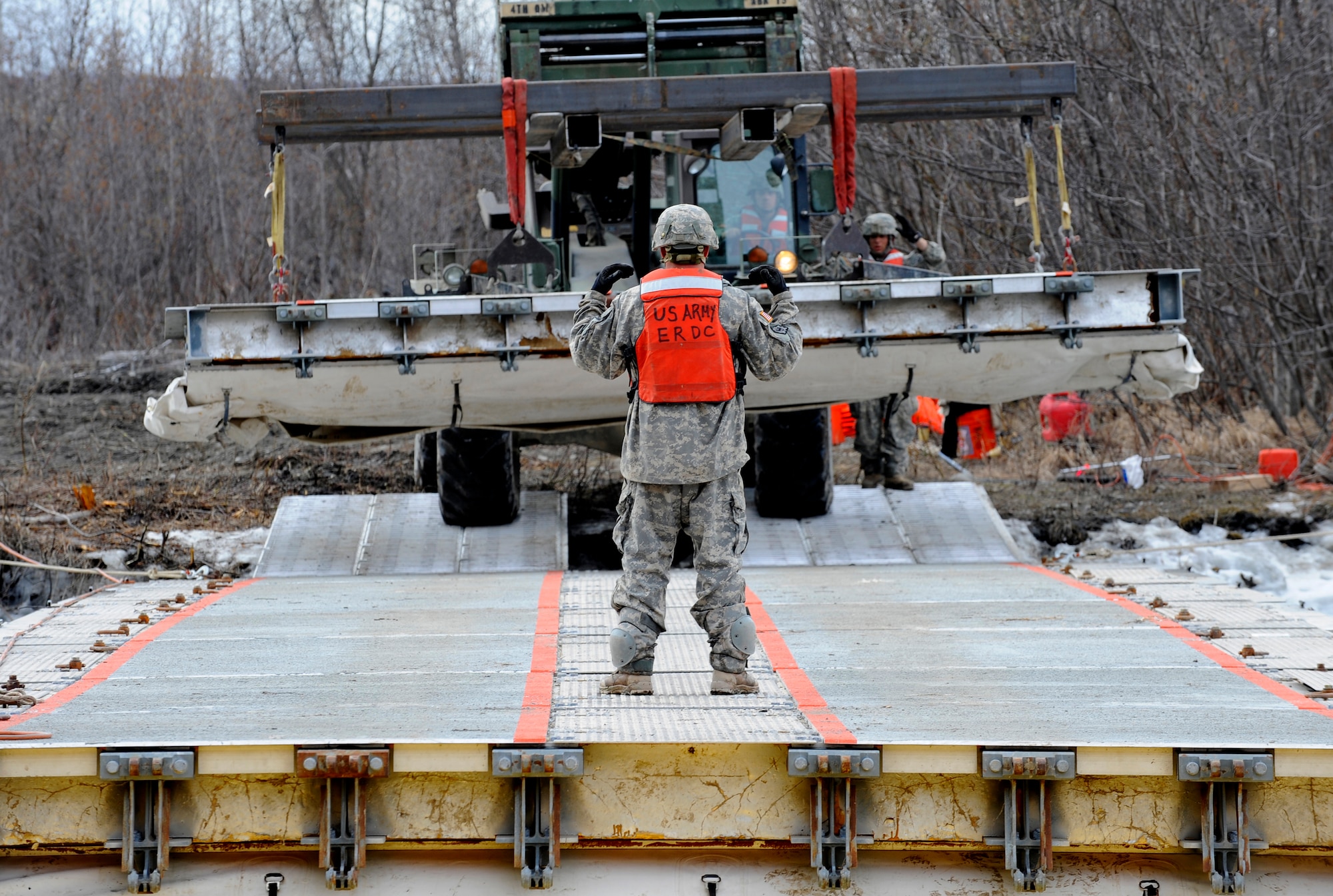 A soldier from the 84th Engineer Support Company, 6th Engineer Battalion, maneuvers the last section of Lightweight Modular Causeway System into place at Fort Richardson, Alaska, April 28. The LMCS is a hybrid fixed bridging system and floating causeway system.  Originally designed for vessel-to-shore bridging applications, it has proven ideally suited for wet-gap crossing solutions.  The load capacity is 70 tons. Here it is being used to respond during Arctic Edge 2010 as an earthquake recovery tool. (U.S. Air Force photo/Staff Sgt. Brian Ferguson)