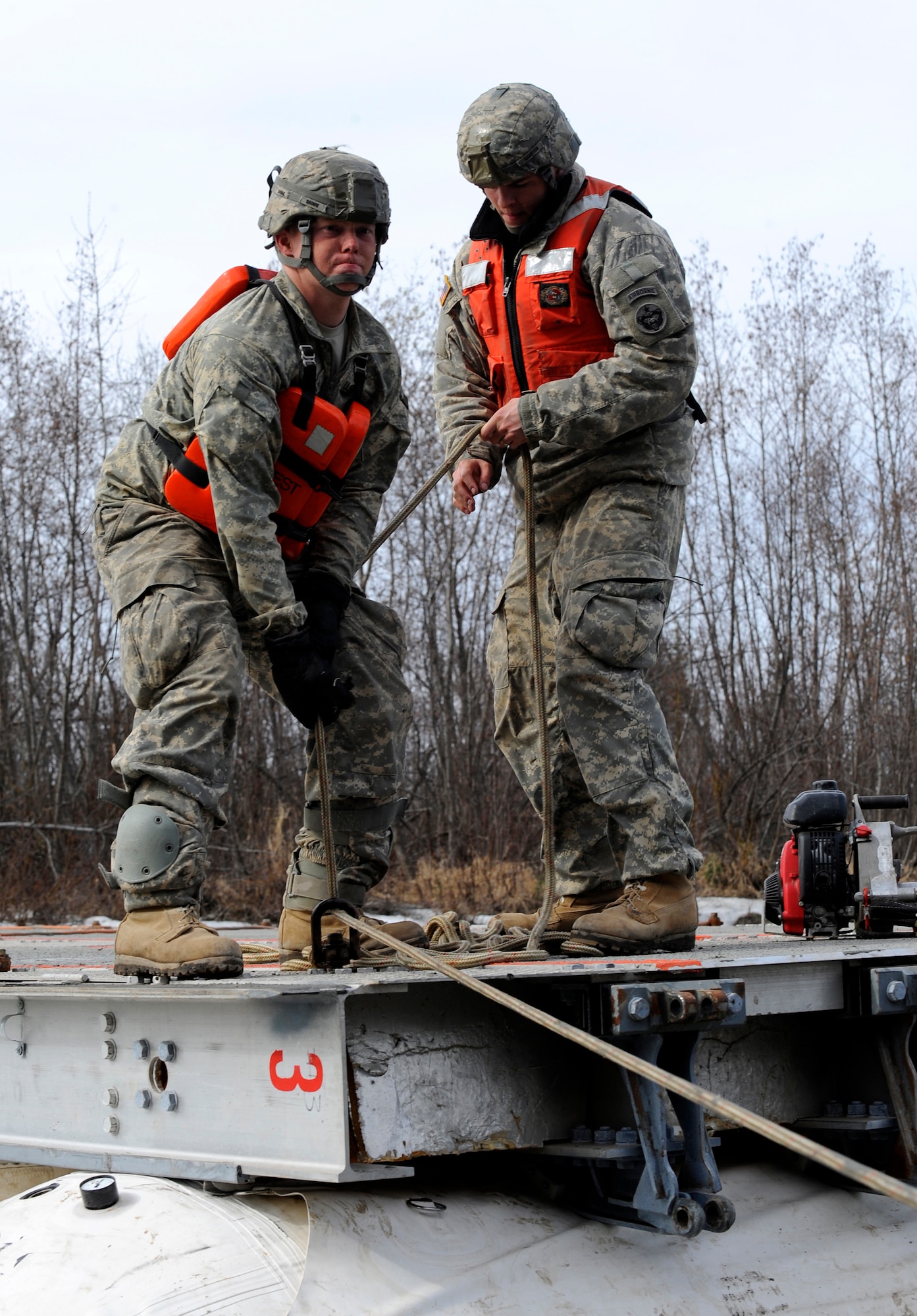 Private 1st Class Keith Brown, left, and Private 1st Class Joshua Hampton, 84th Engineer Support Company, 6th Engineer Battalion, adjust the mooring lines of a Lightweight Modular Causeway System during testing at Fort Richardson, Alaska, April 28. The LMCS is a hybrid fixed bridging system and floating causeway system.  Originally designed for vessel-to-shore bridging applications, it has proven ideally suited for wet-gap crossing solutions.  The load capacity is 70 tons. Here it is being used to respond during Arctic Edge 2010 as an earthquake recovery tool. (U.S. Air Force photo/Staff Sgt. Brian Ferguson)