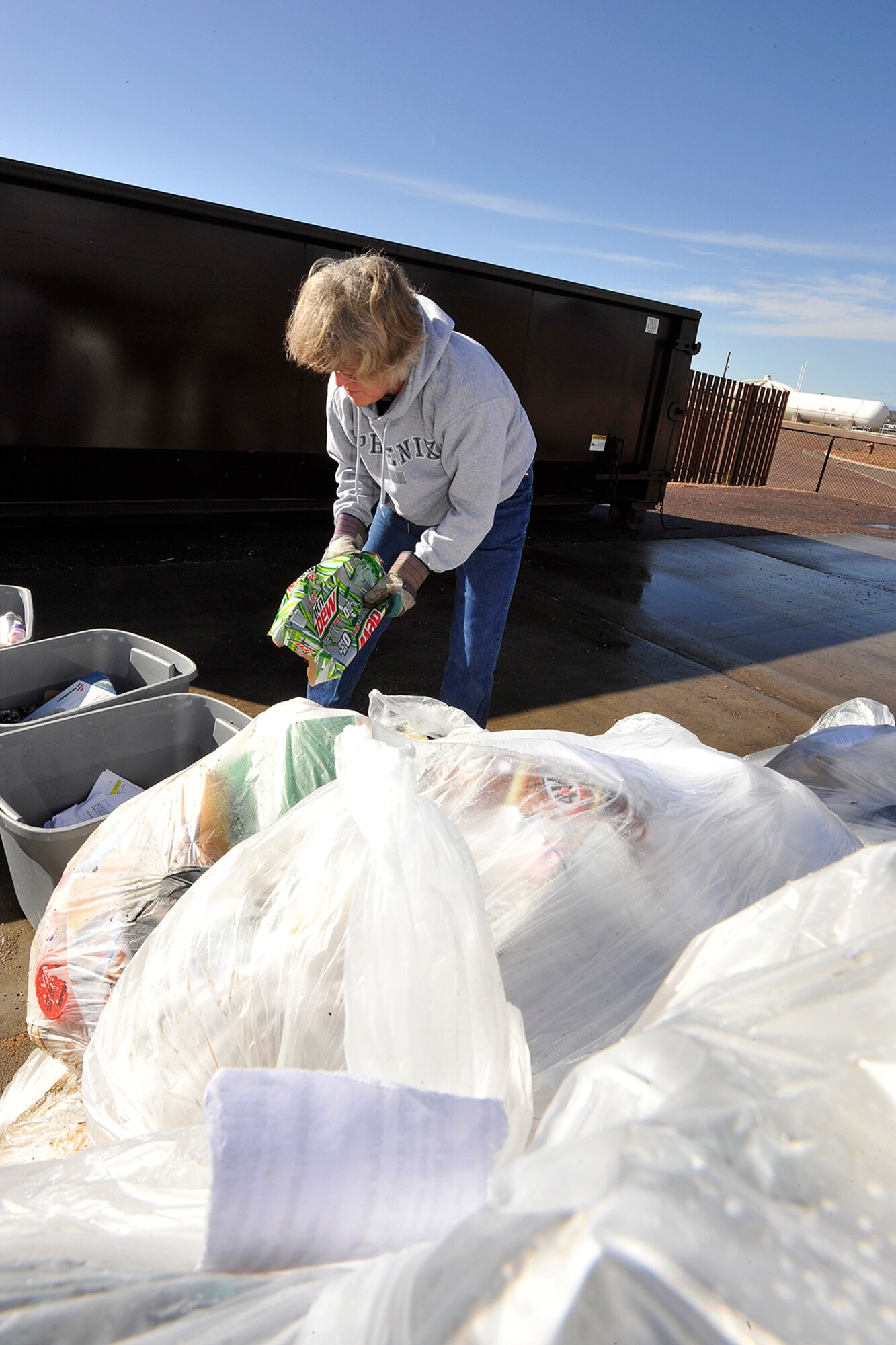 Laurie Baker, Booz Allen Hamilton environmental consultant, pulls cardboard April 22 from a bag of trash headed for the landfill that could have been recycled. Ms. Baker performs trash audits on Peterson AFB to show how much material could be recycled. The Earth Day audit found 45.8 pounds of plastics, 56.6 pounds of white paper, 21.2 pounds of aluminum and 13.8 pounds of cardboard that could have been recycled. The results will be used by the 21st Civil Engineer Squadron and building managers to design recycling programs. (U.S. Air Force photo/Rob Bussard)