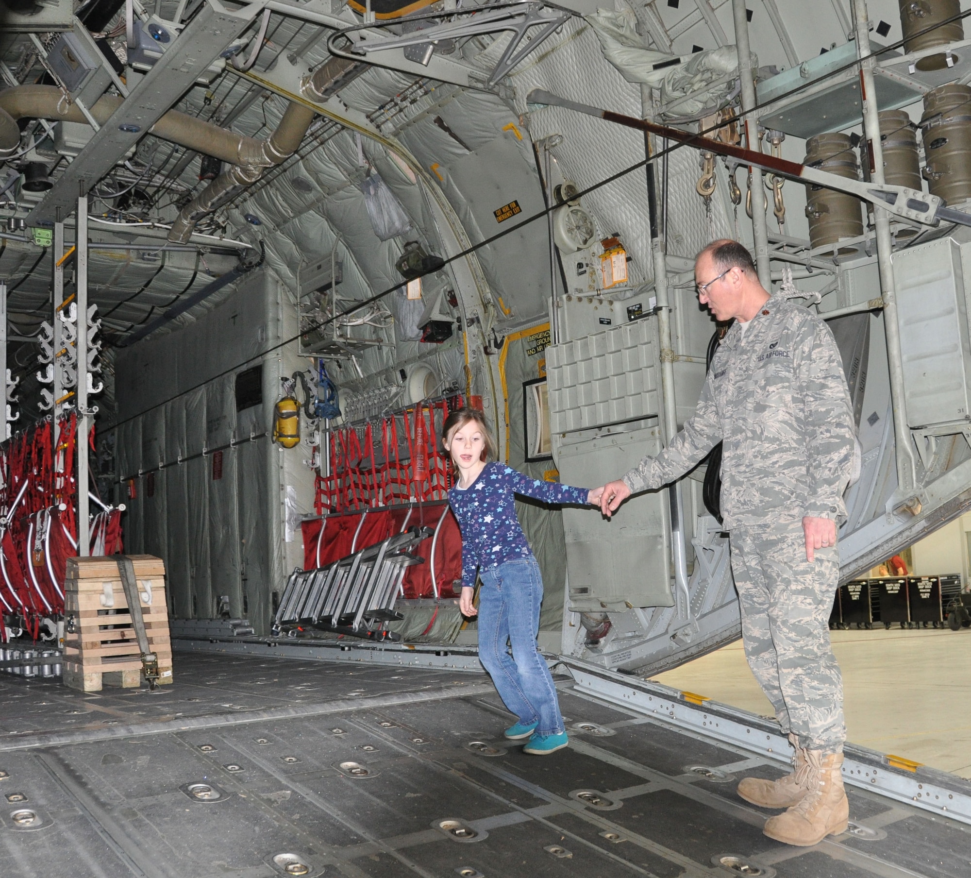 Evangeline Christoff, 6, drags dad, Maj. Steve Christoff, 934th Civil Engineering Squadron, up the ramp of a C-130 Hercules aircraft at the 934th Airlift Wing?s first Take Your Child To Work Day? April 29. 