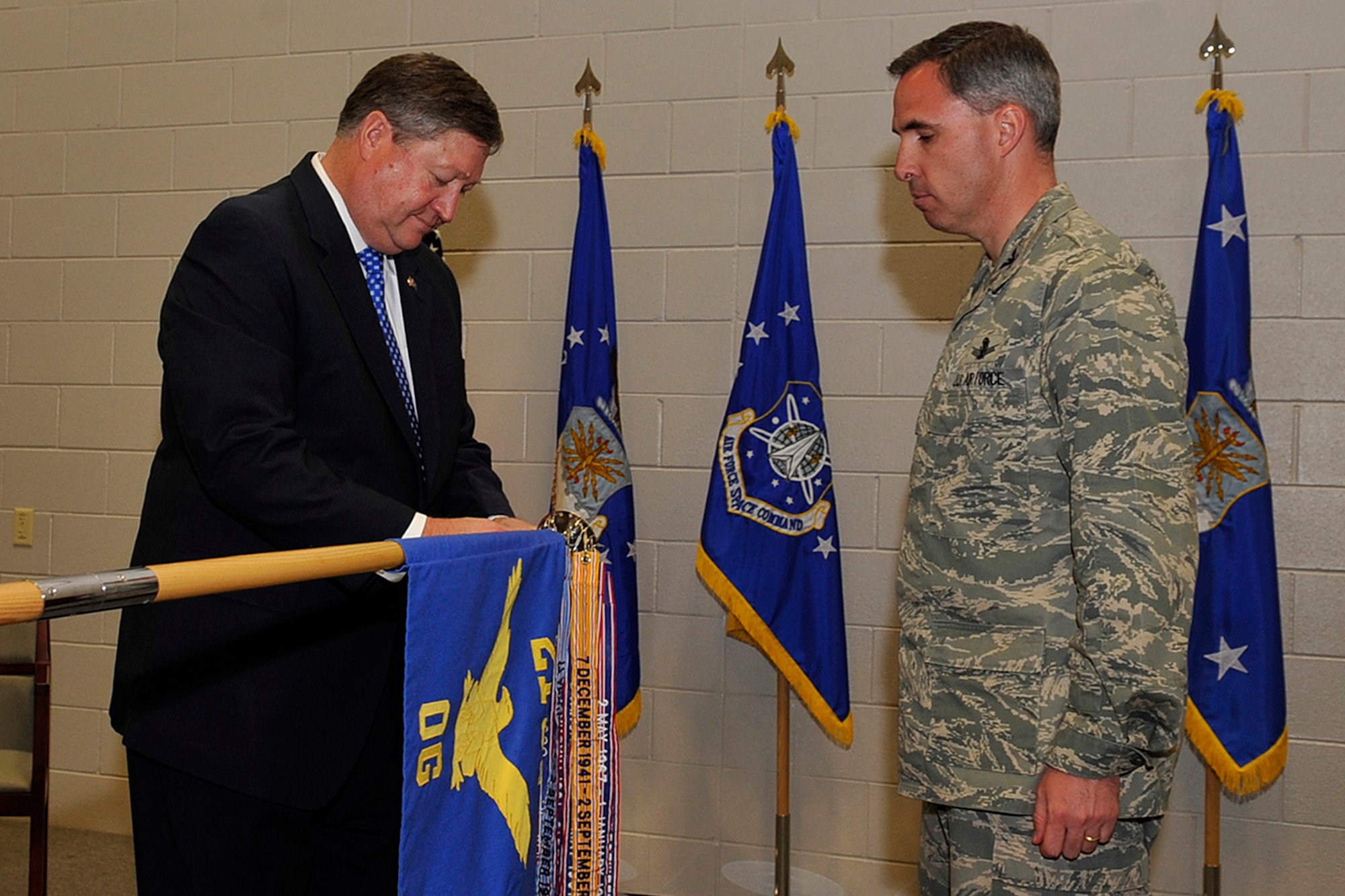 PETERSON AIR FORCE BASE, Colo. -- Michael Donley, secretary of the Air Force, attaches the Meritorious Unit Award to the 21st Operations Group guidon as Col. Stephen N. Whiting, 21st Space Wing commander, looks on. Secretary Donley presented the MUA to the 21st OG for meritorious conduct in direct support of combat operations from June 2, 2007 to July 7, 2009. The ceremony was April 13 at Building 2028, the new 76th Space Control Squadron facility. (U.S. Air Force photo/Rob L. Bussard)