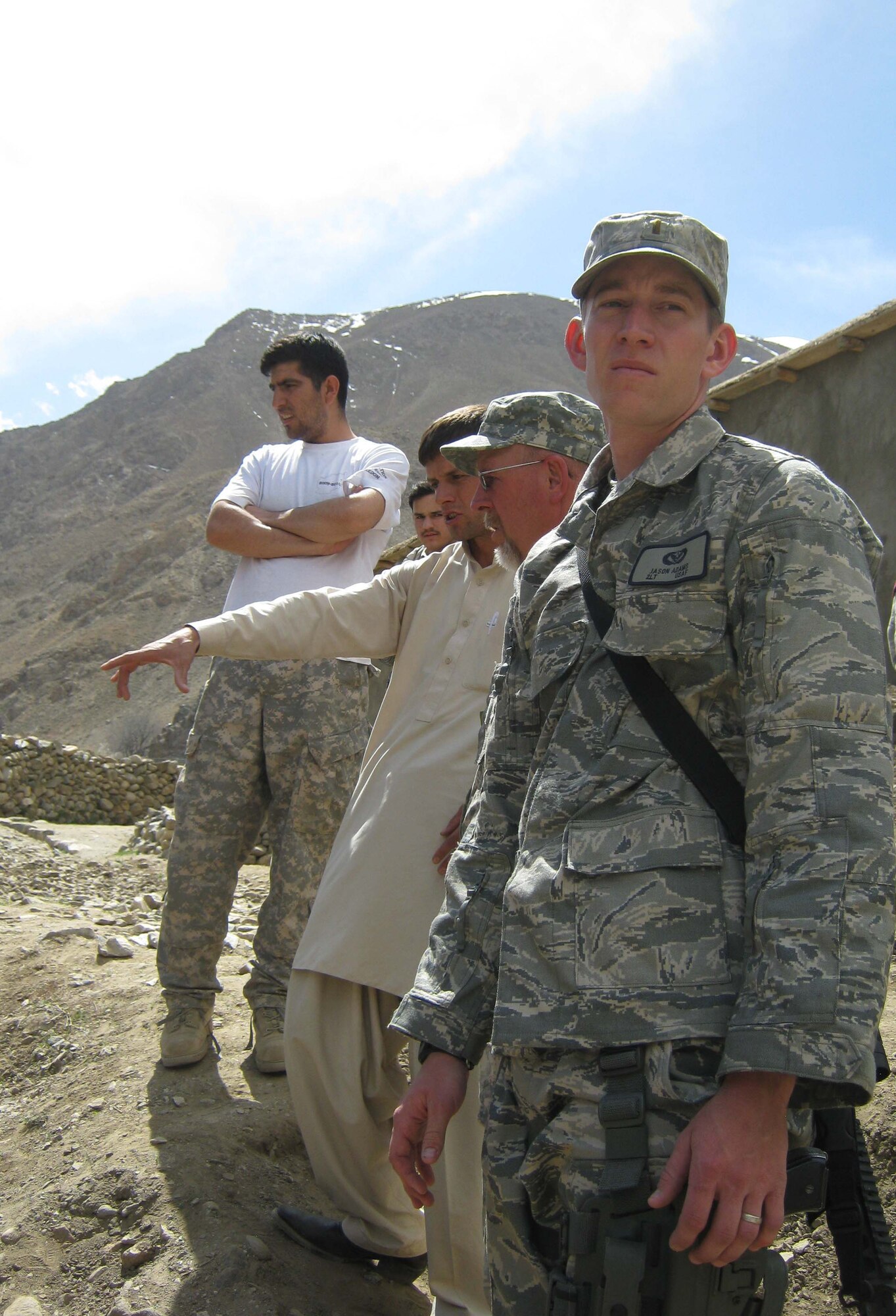 Second Lt. Jason Adams (front), Provincial Reconstruction Team Panjshir civil engineer, looks at the Pawat School construction site, while Scott Davis (second from front), U.S. Army Corps of Engineers, listens to a presentation by the school?s contractor, Ghulam Hazrat. The school construction site was one of six stops the engineers made during a March 27 mission around the province. (Photo by U.S. Air Force 2nd Lt. Jason Smith, PRT Panjshir Public Affairs)