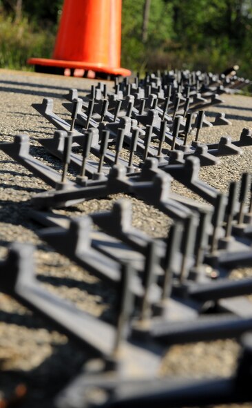 MOODY AIR FORCE BASE, Ga. -- Spike strips are laid across the road during the 822nd Security Forces Squadron’s validation exercise as part of the mock entry control point here April 27. Each spike was covered with a plastic tip to ensure that no tires were accidentally punctured. (U.S. Air Force photo by Airman 1st Class Benjamin Wiseman/RELEASED)