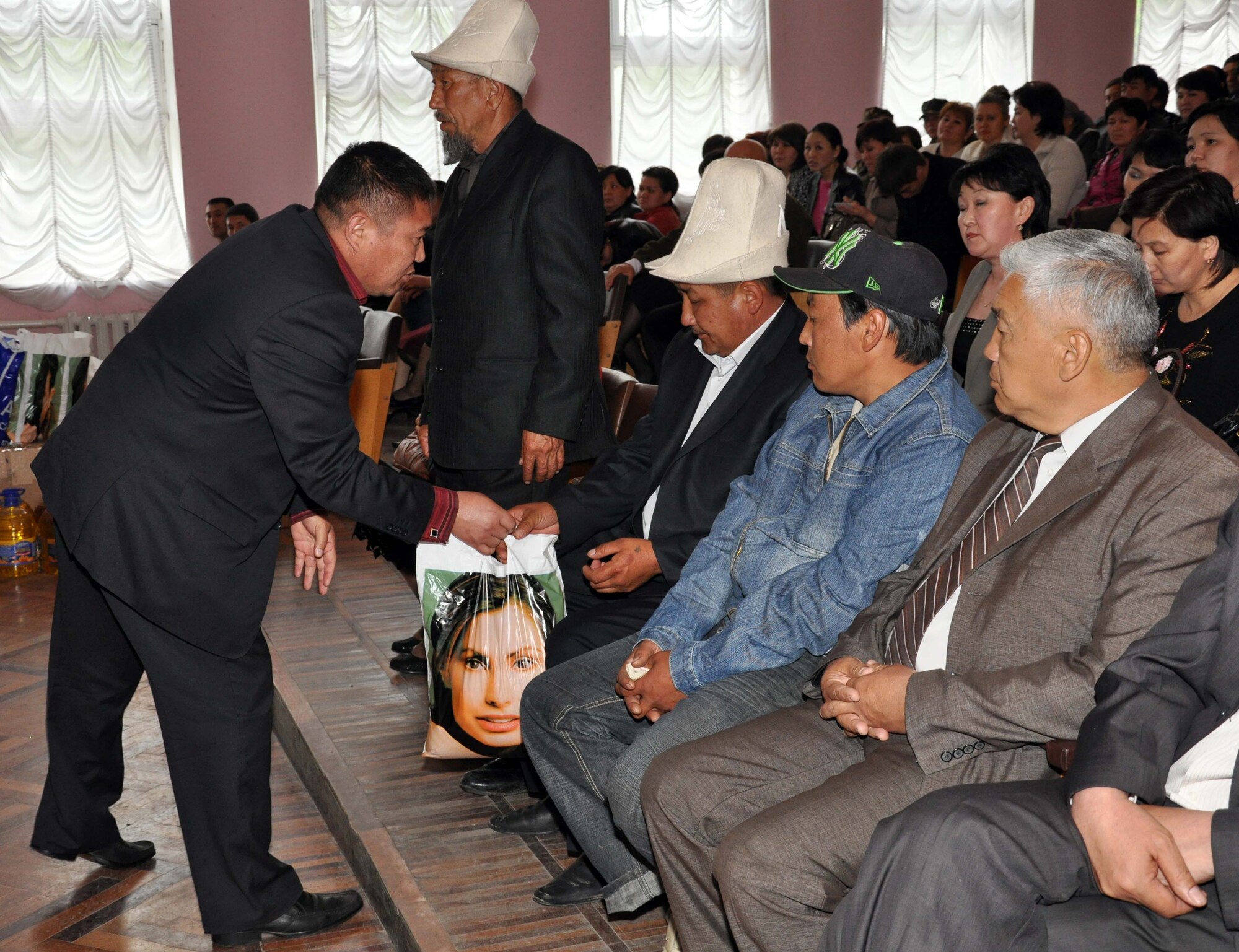 A TokMok dignitary hands a gift bag to the families of five fallen Kyrgyz men who, among many, were slain during the recent unrest in Kyrgyzstan.  U.S. Airmen from the Transit Center at Manas attended the ceremony to honor them and donated dry and household goods to assist their surviving family members. (U.S. Air Force photo/Staff Sgt. Carolyn Viss)