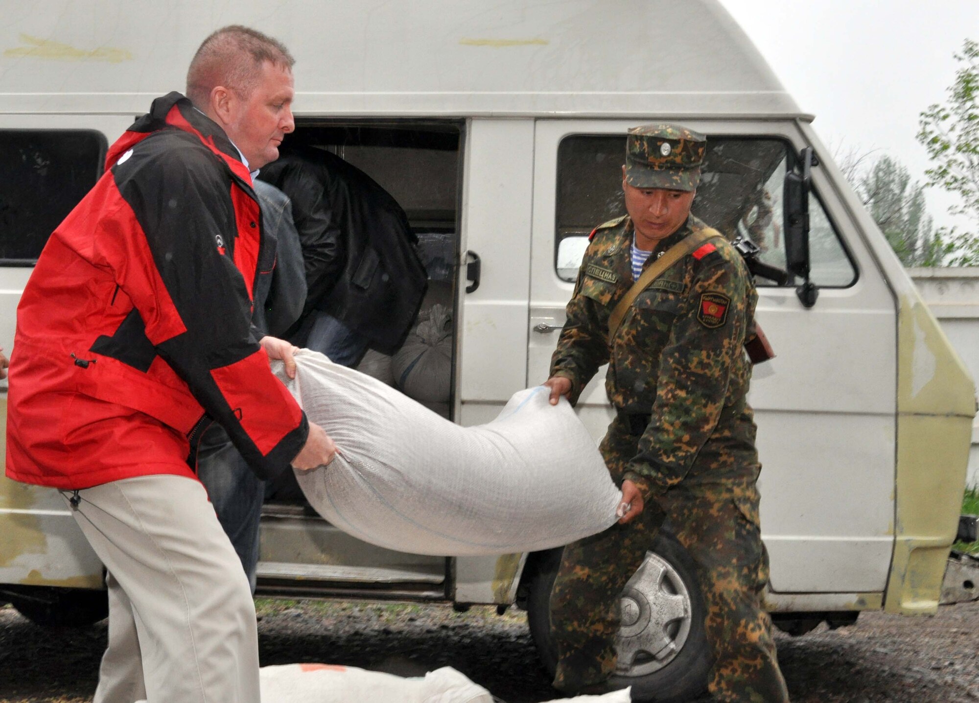 376th Air Expeditionary Wing Command Chief Master Sgt. Jim Dowell helps a Kyrgyz soldier unload flour from a Transit Center at Manas truck in TokMok, Kyrgyzstan, April 29, 2010. Airmen honored five fallen Kyrgyz men who, among many, were slain during the recent unrest in Kyrgyzstan. The U.S. Airmen donated dry and household goods to assist their surviving family members. (U.S. Air Force photo/Staff Sgt. Carolyn Viss)