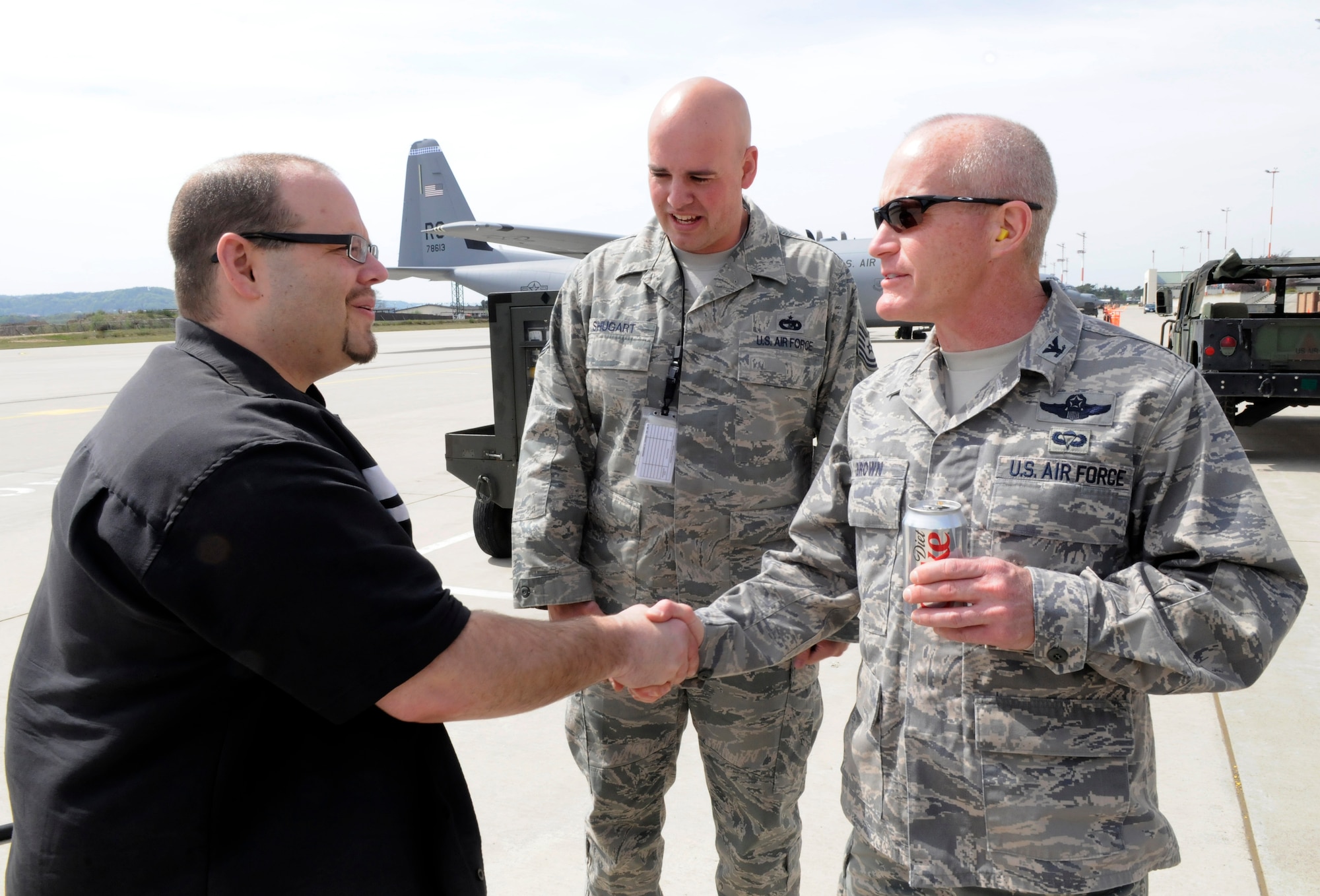 Mason Mastroianni, artist of B.C. comic strip, along with his escort U.S. Air Force Tech. Sgt. Shane Shugart, 435th Contingency Response Group (CRG), shakes hands with Col. Timothy Brown, 435th CRG commander, while visiting the flightline, Ramstein Air Base, Germany, April 29, 2010. While at Ramstein, Airmen took professional cartoonist from the National Cartoonist Society around visiting various locations like the flight tower, flightline, fire department, C-130 J Super Hercules, C-17 aircraft and the 435th Contingency Response Group. (U.S. Air Force photo by Airman 1st Class Brittany Perry)