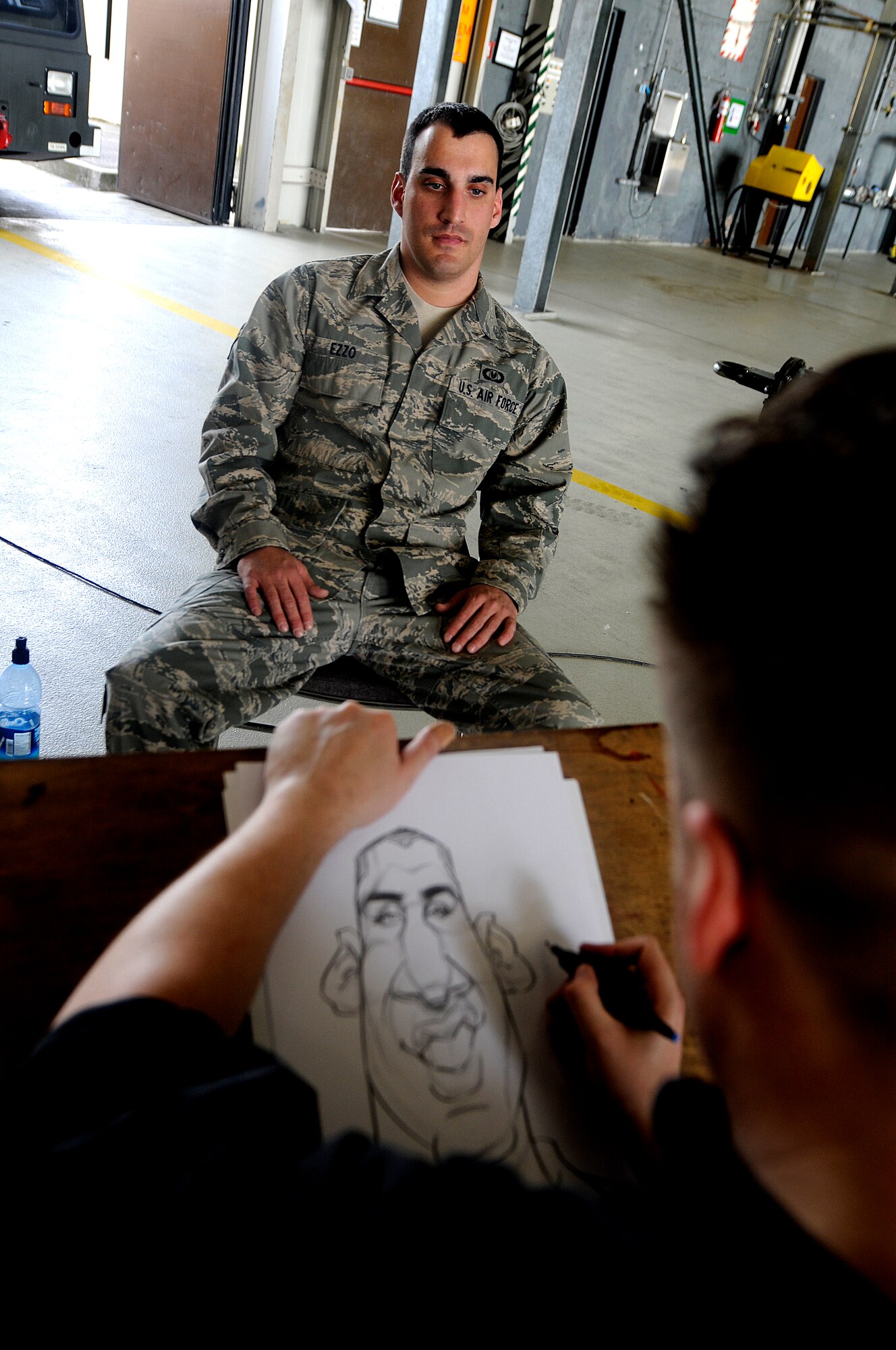 Mr. Ed Steckley, MAD magazine artist for DC comics, sketches U.S. Air Force Airman 1st Class Jonathan Ezzo, 86th Operation Support Squadron equipment technician, in the dual bay hanger, Ramstein Air Base, Germany, April 29, 2010. Several cartoonists took part in a two-day tour of the Kaiserslautern Military Community, visiting with wounded warriors, military members and their families. (U.S. Air Force photo by Airman 1st Class Brea Miller)